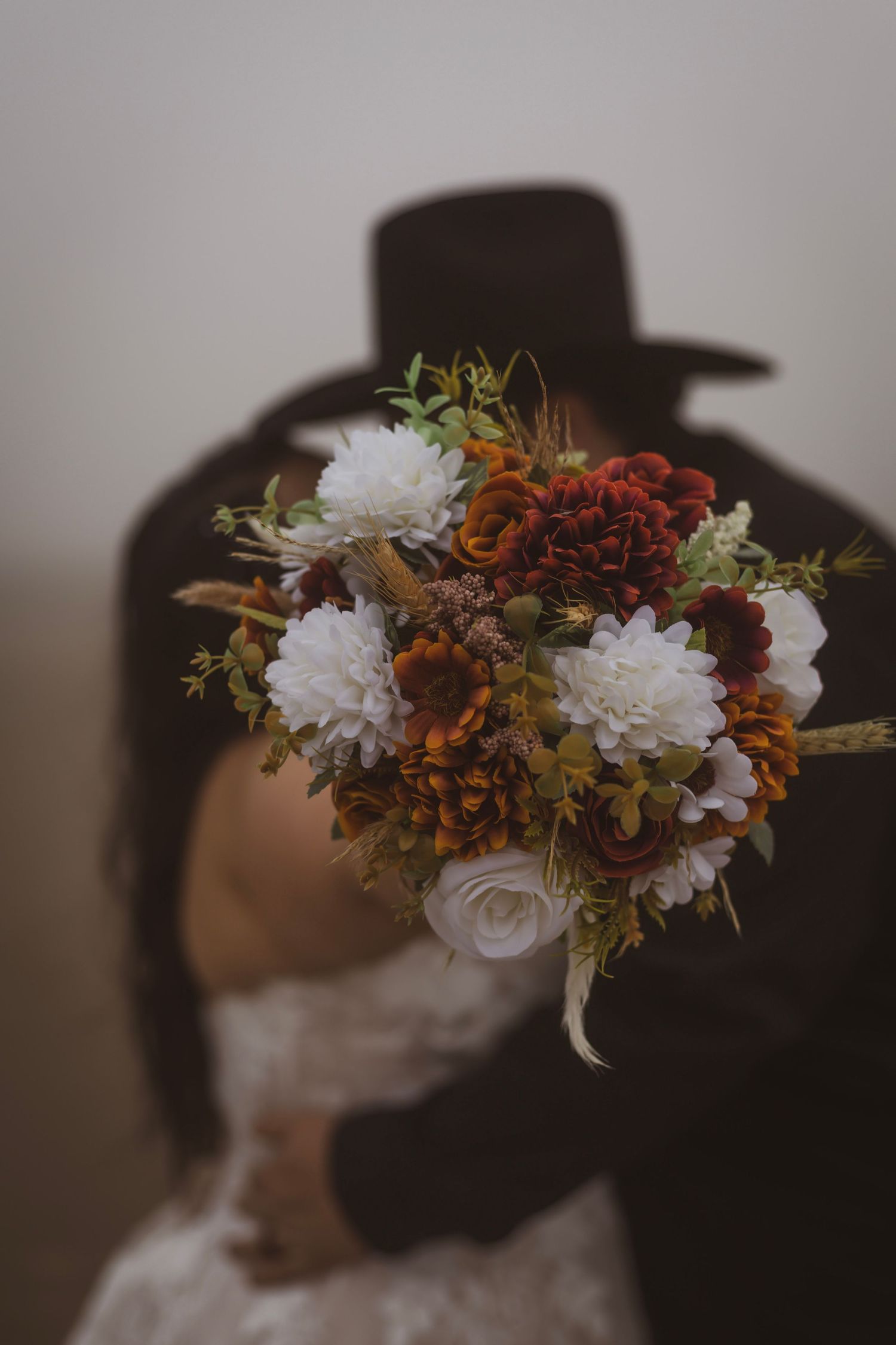 Floral crown with white chrysanthemums and autumn-colored foliage against dark background.
