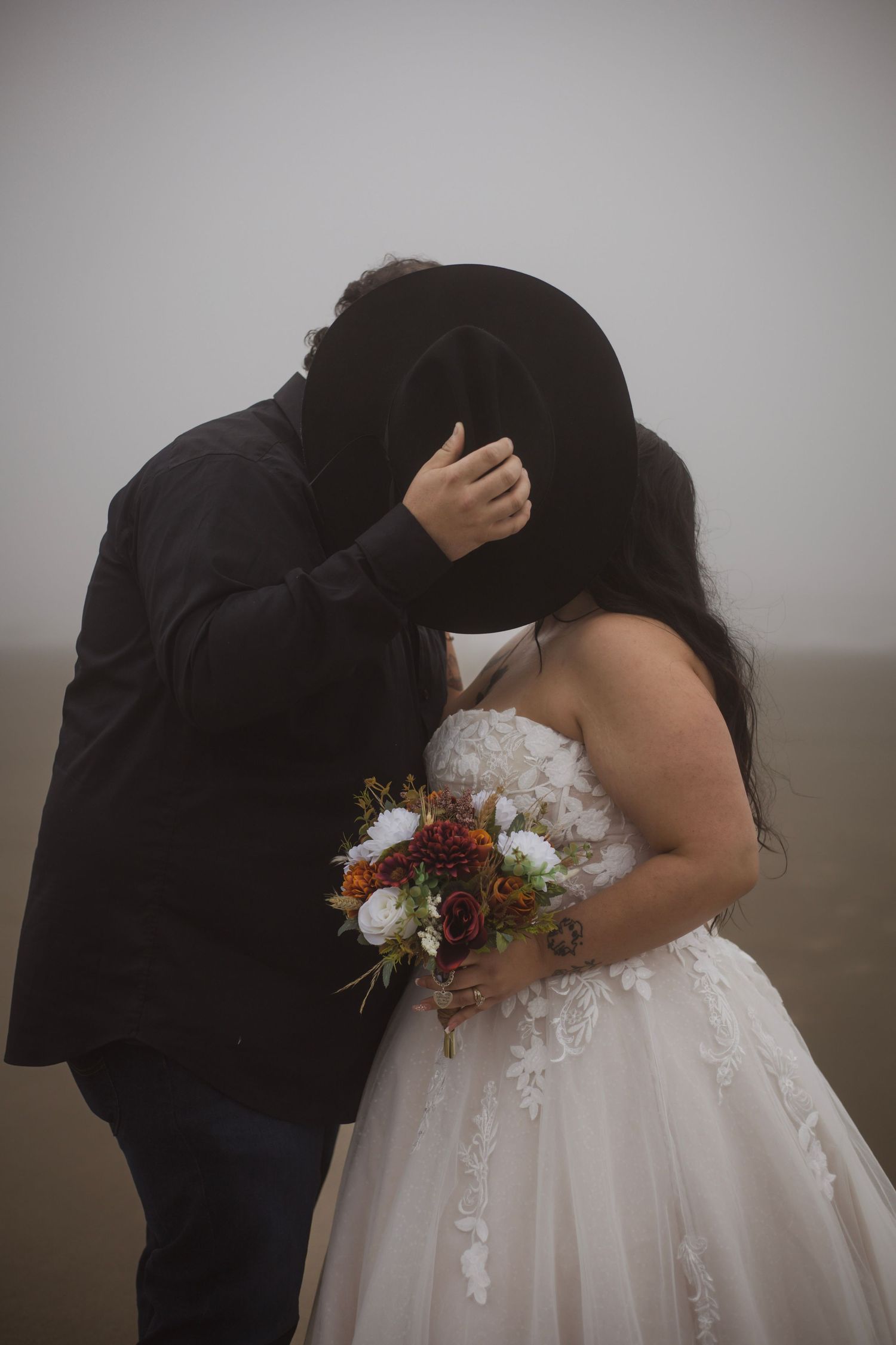 Intimate wedding couple embrace captured in moody, artistic style.