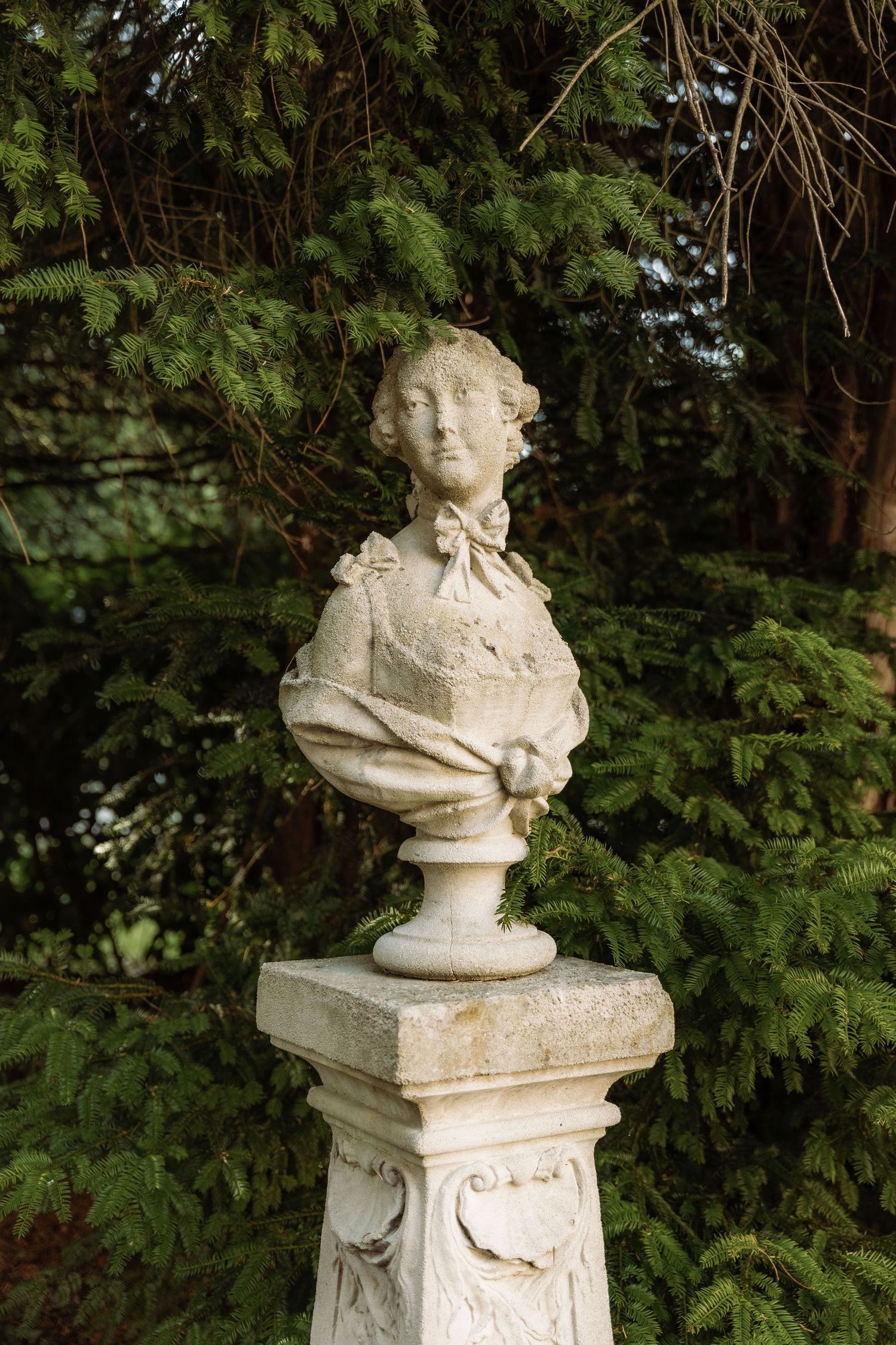 A statue of a woman with greenery behind