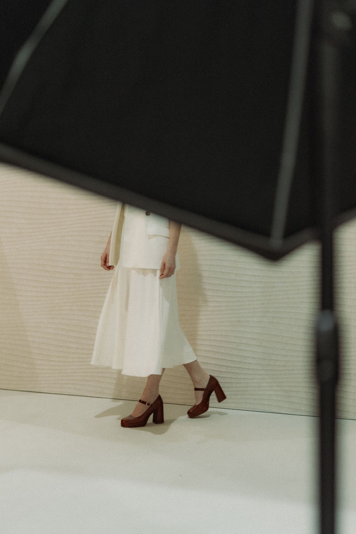 Behind the scenes from a fashion shoot. A woman with white clothes poses for the picture