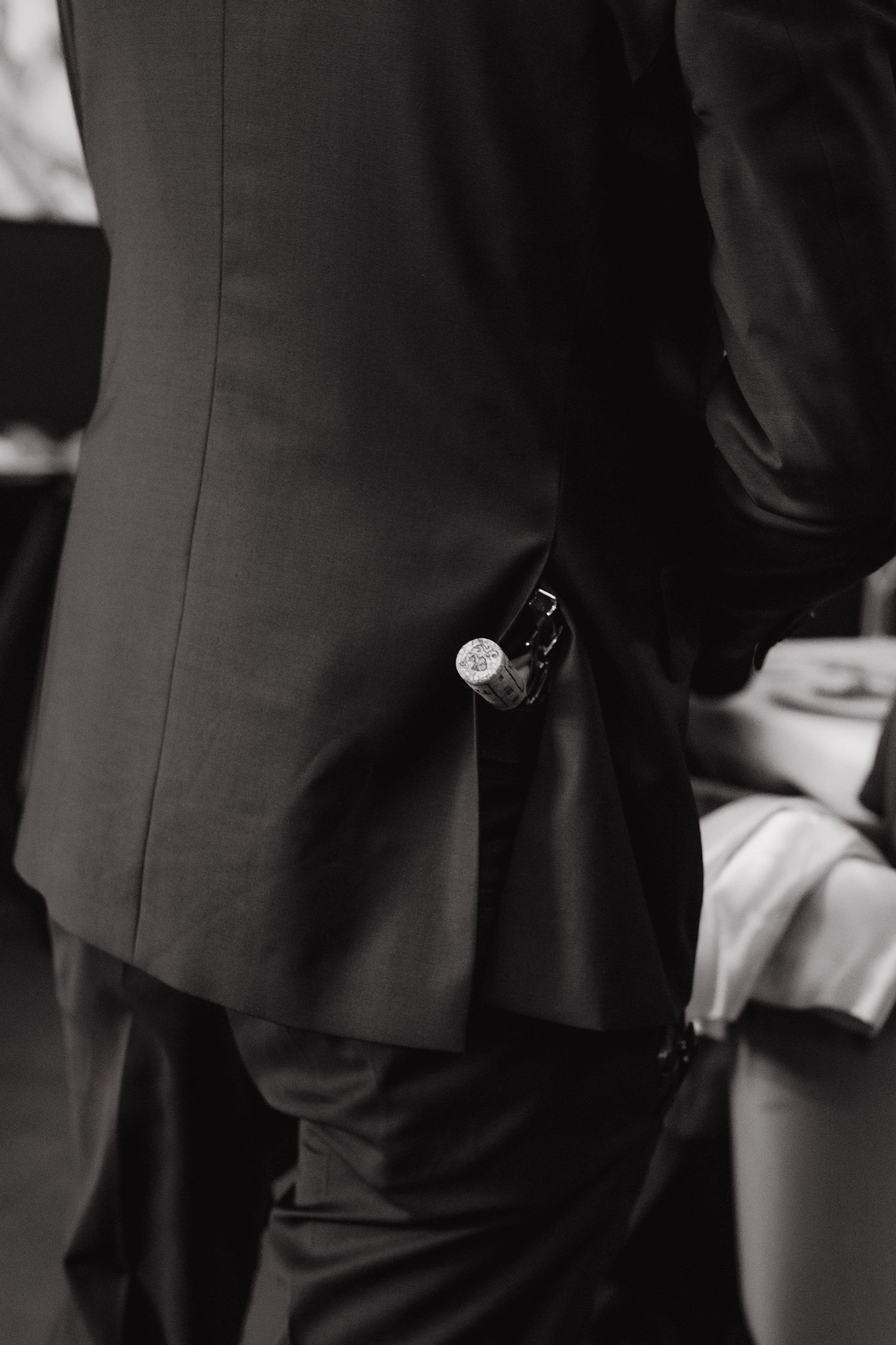the cap of a wine bottle can be seen in the pocket of a waiter