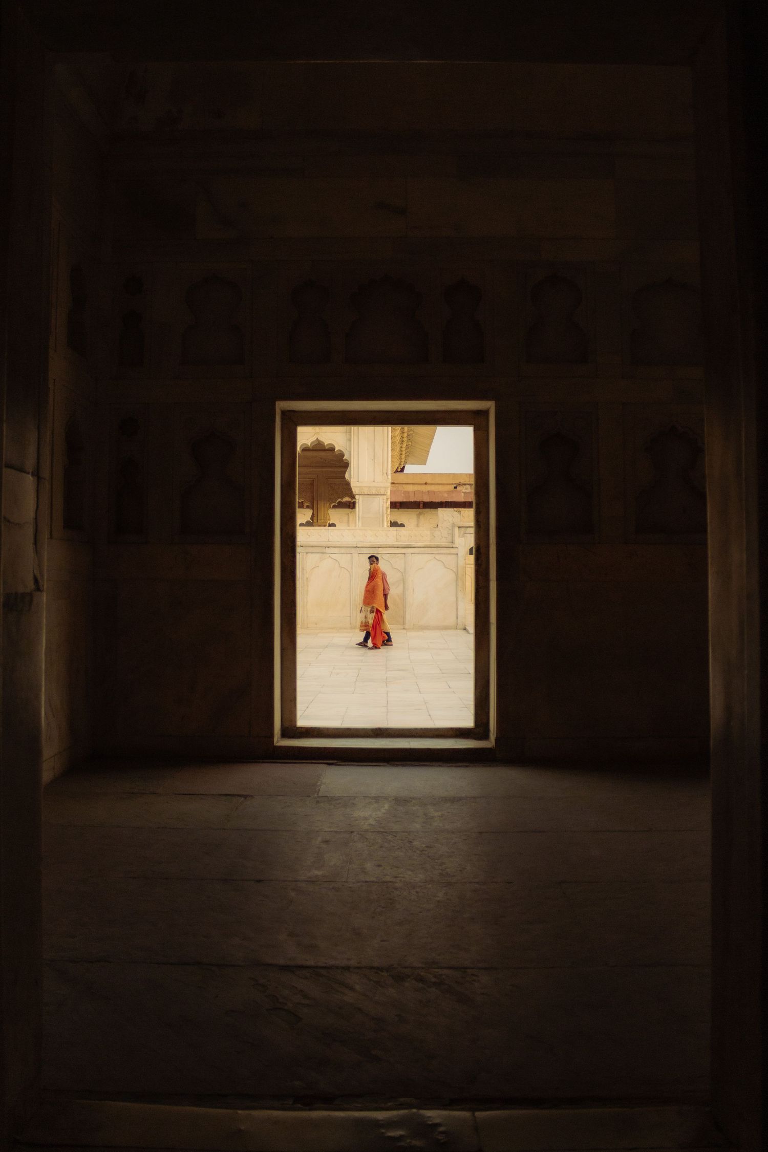 A couple walks past a gateway in Agra Temple, India