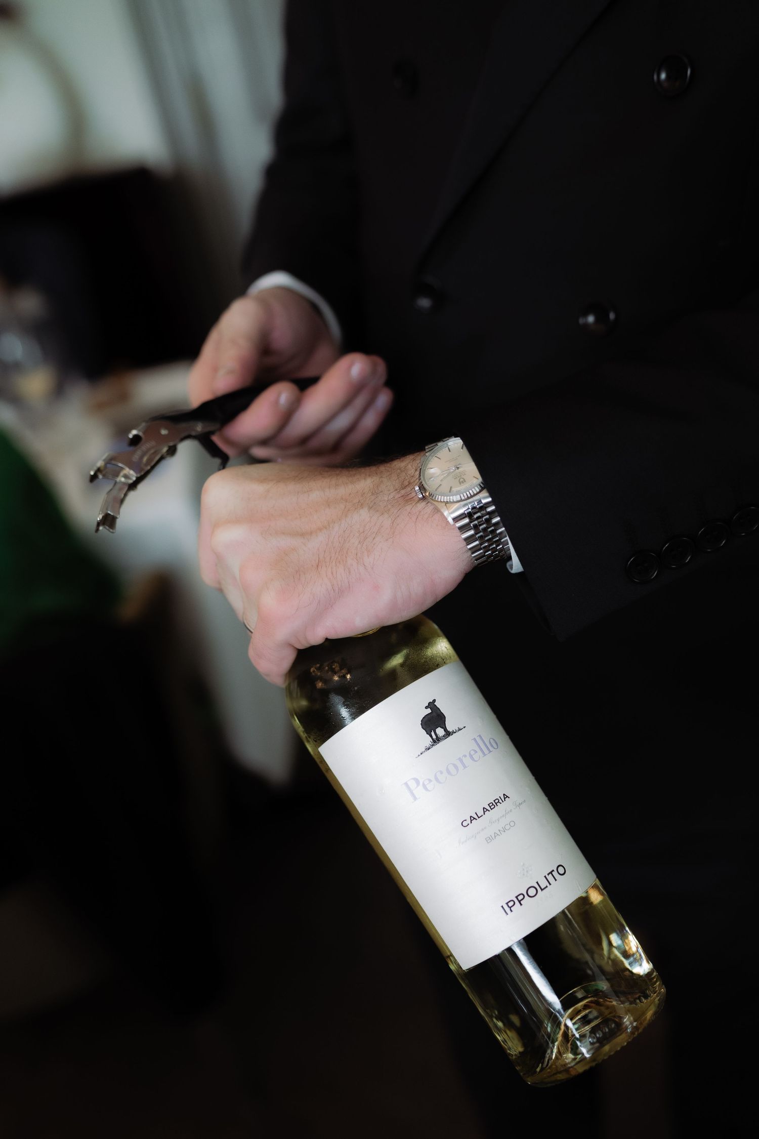 a waiter is opening a bottle of wine