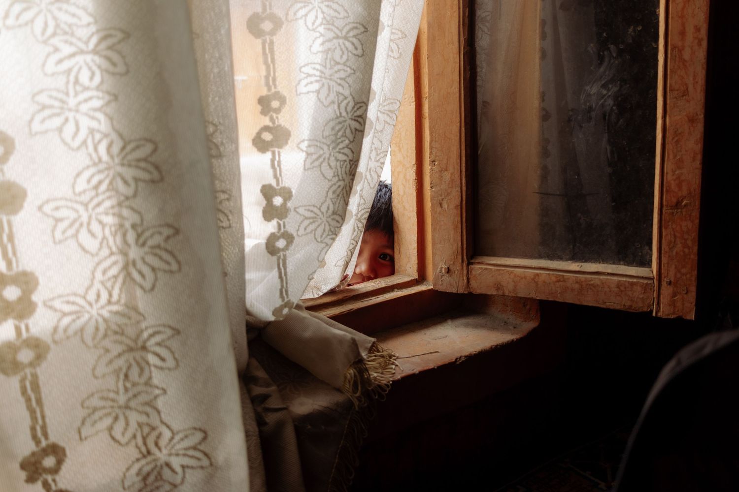 A child peeks through a window in Leh, Ladakh