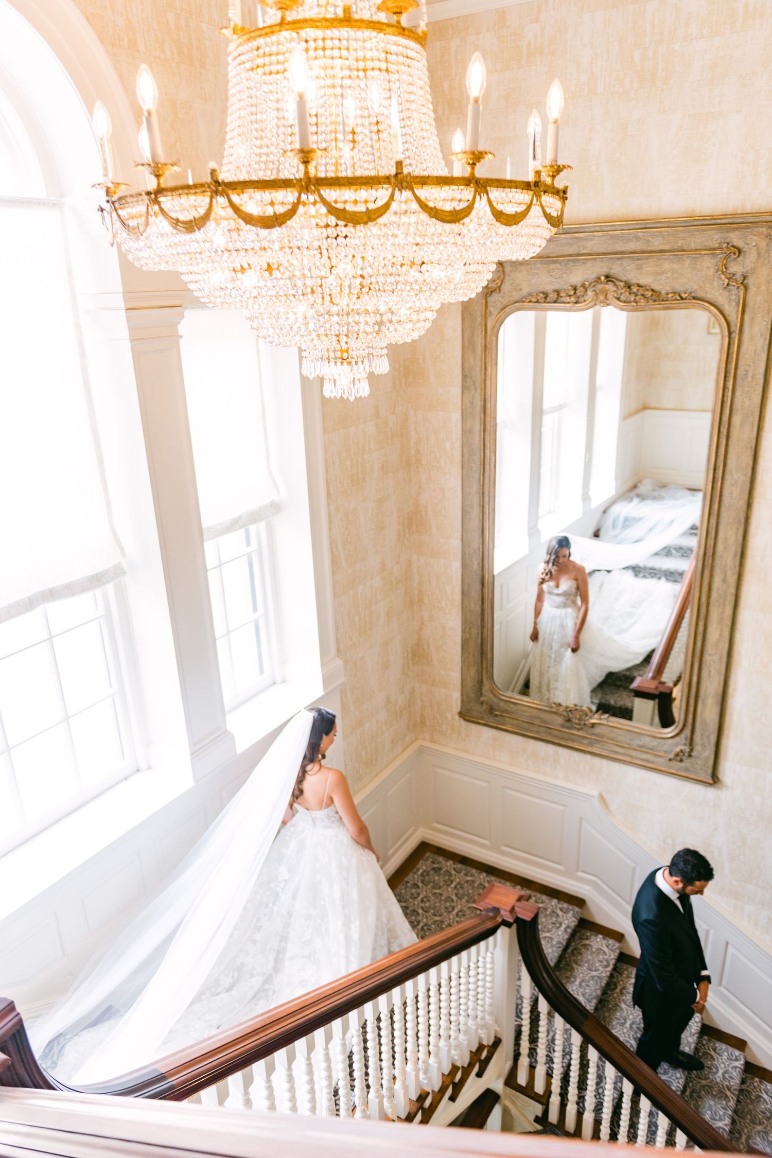 Bride and groom during their first look at Graydon Hall Manor staircase with large mirror, photographed by a Toronto wedding photographer.