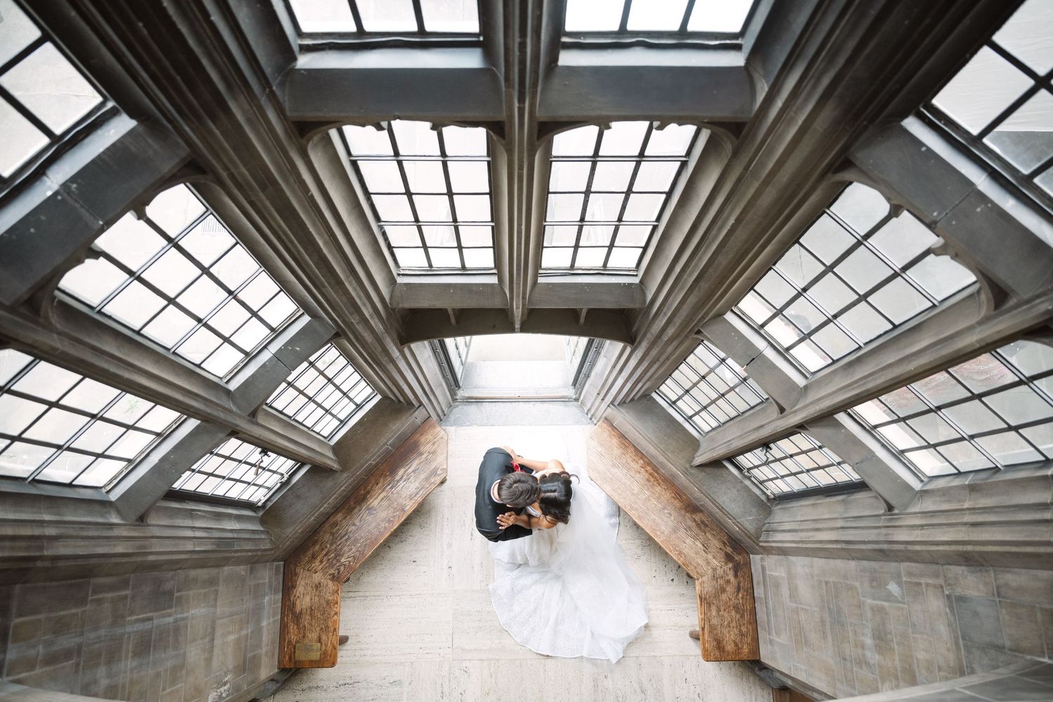 Architectural wedding photo showcasing dramatic skylight ceiling and stone walls.