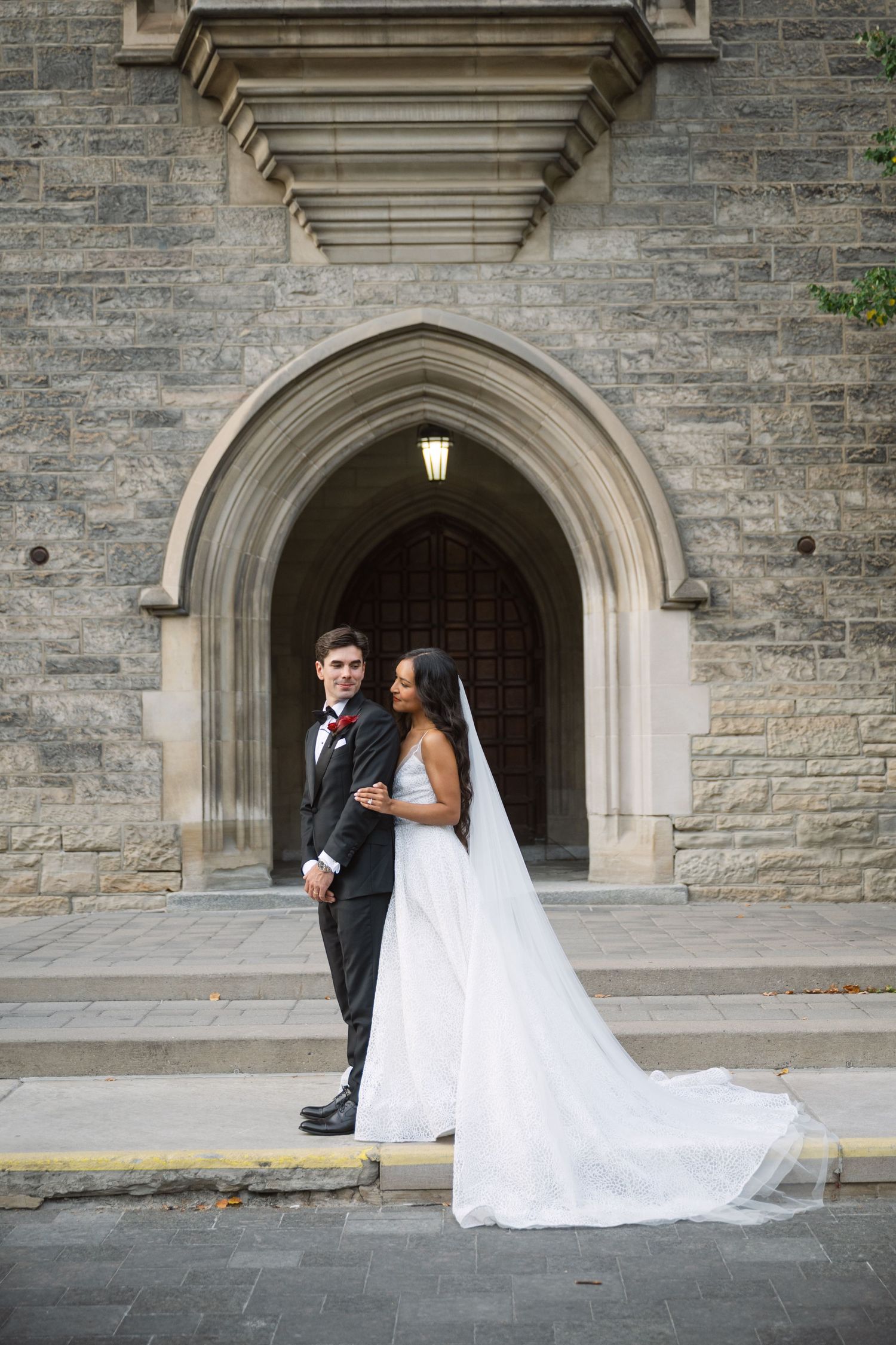 Wedding portrait against stone archway architecture with flowing white dress and veil.