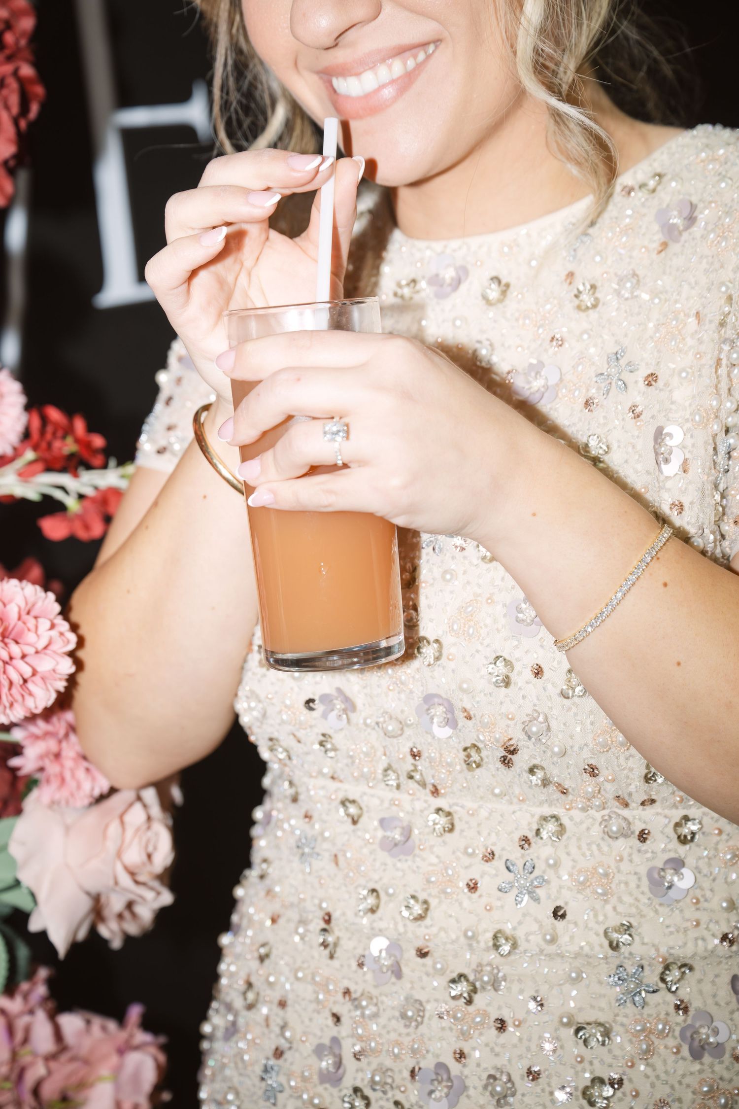 Close-up of sparkling beaded wedding dress with champagne glass.