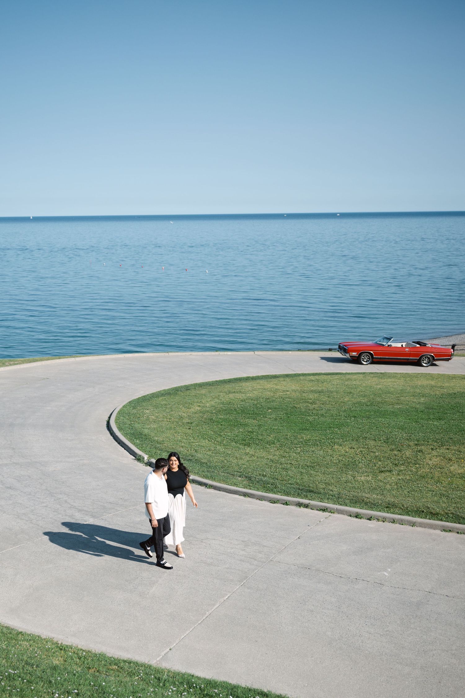 Couple engagement photoshoot at RC Harris Treatment Plant with a vintage red car by Lake Ontario, captured by a Toronto wedding photographer