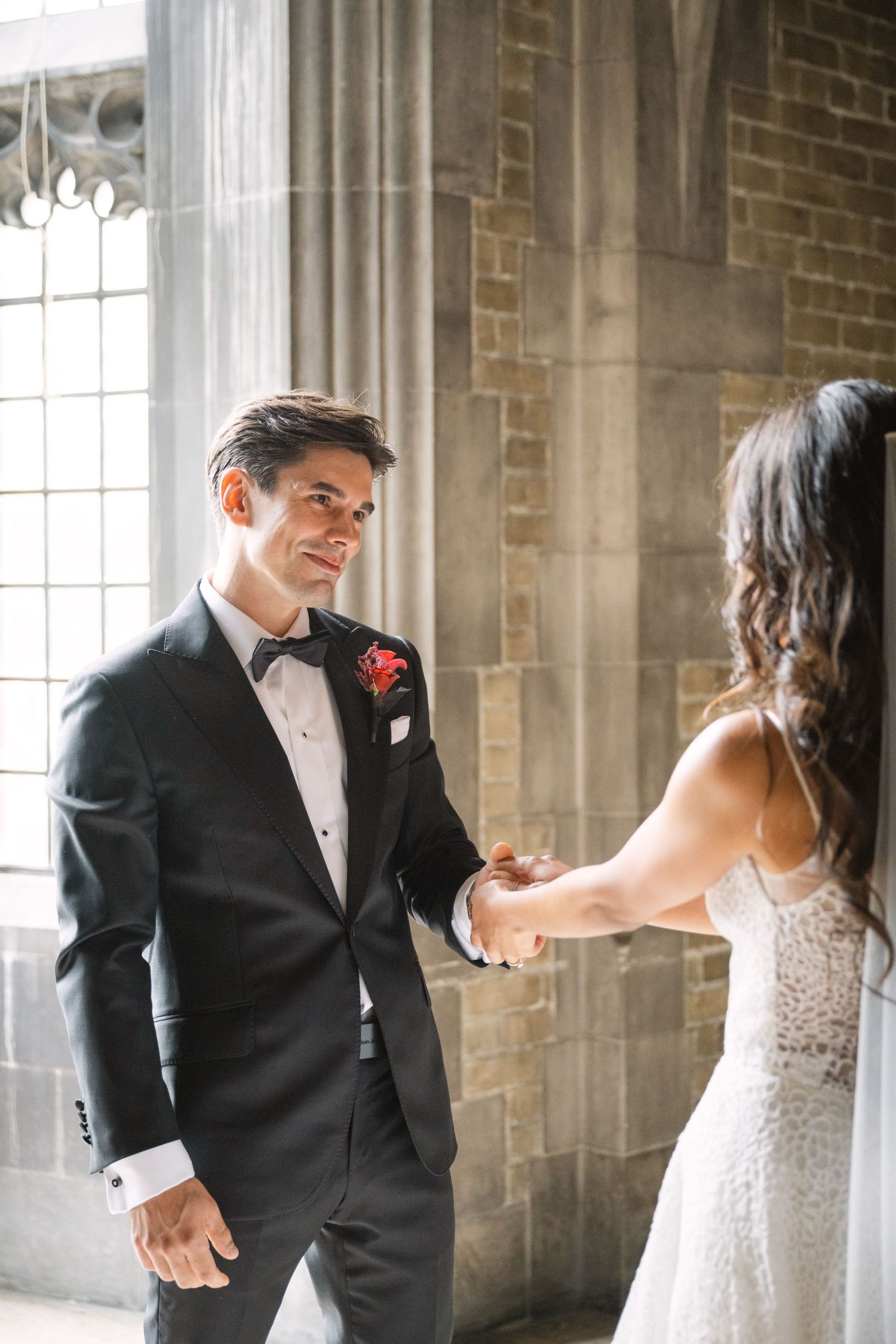 Candid wedding moments captured in stone hallway with gothic architecture.