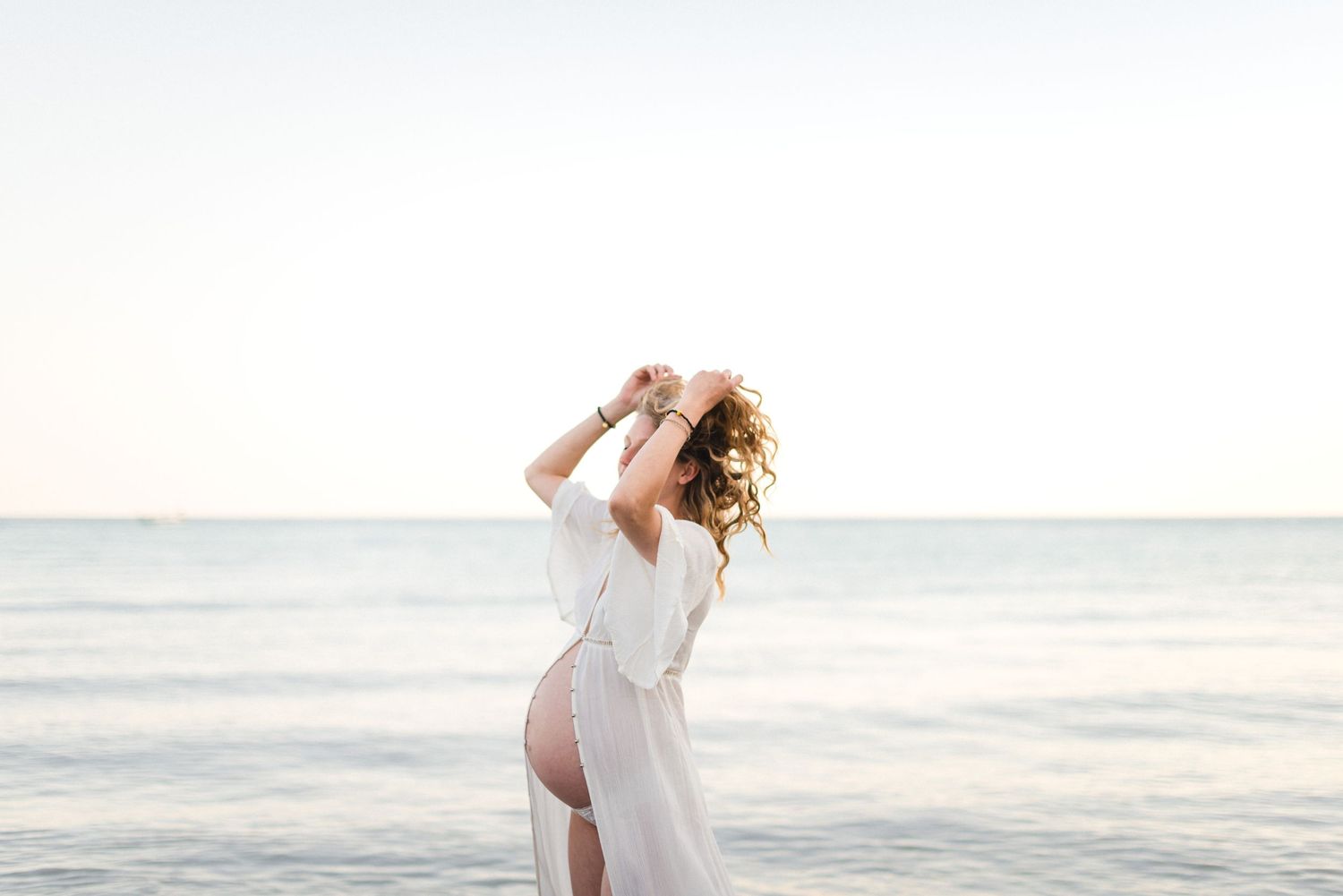 Minimalistic maternity photo at Scarborough Bluffs with lake and pastel sunset skies, photographed by a Toronto lifestyle photographer.