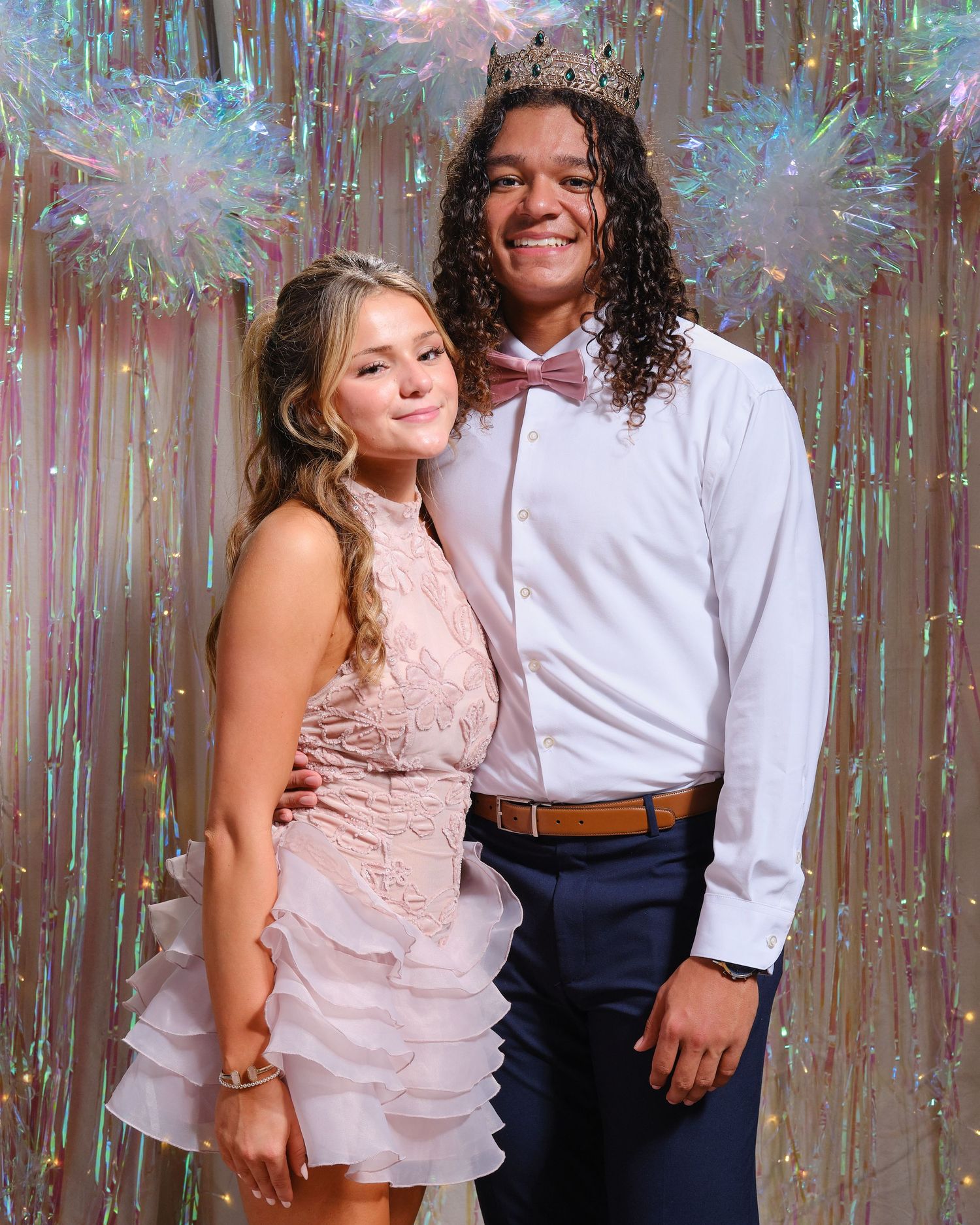 Formal portrait of smiling homecoming couple with sparkly decorative background