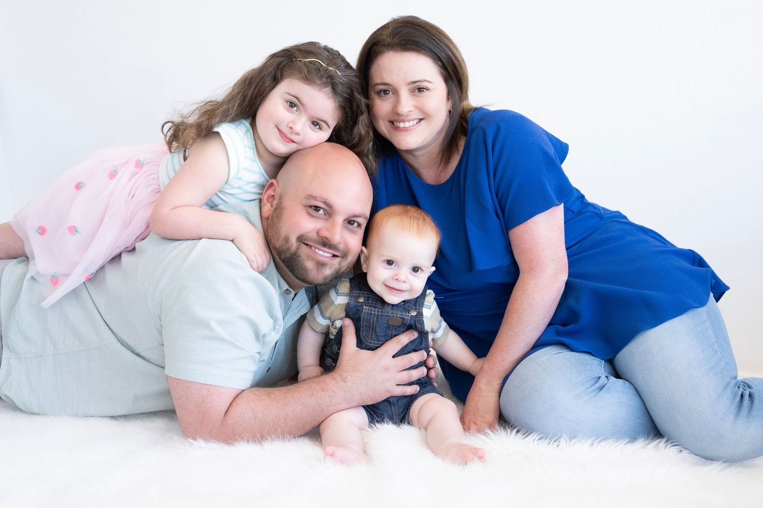 Family portrait series with parents and baby on white background.