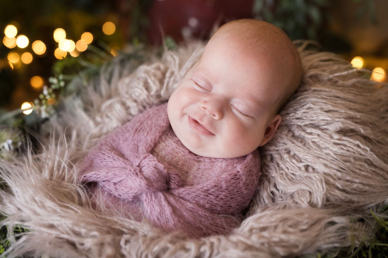 Peaceful newborn baby sleeping on plush fur with bokeh lights in background.
