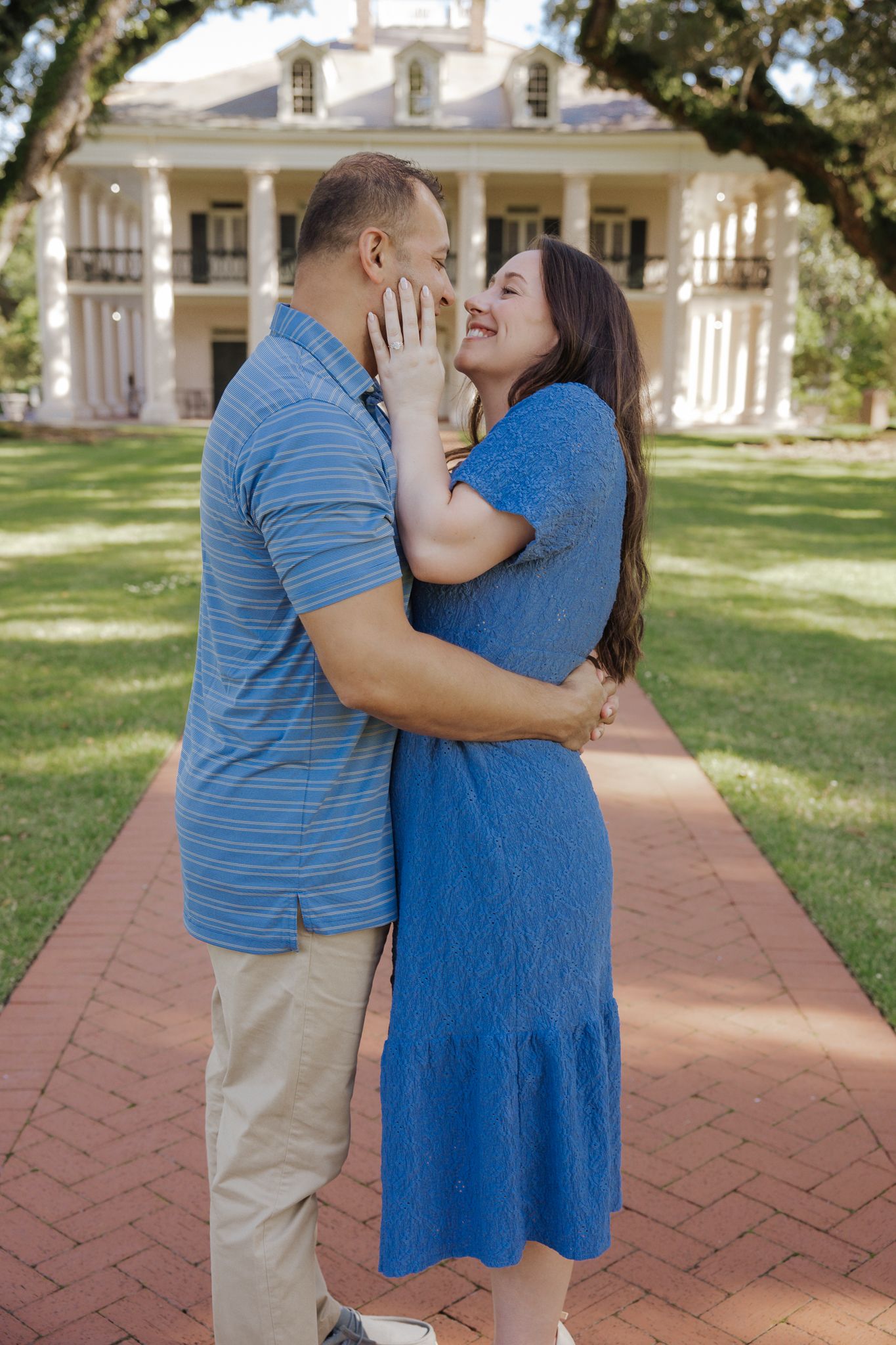 Couple embracing and laughing in front of a grand white Southern plantation home.
