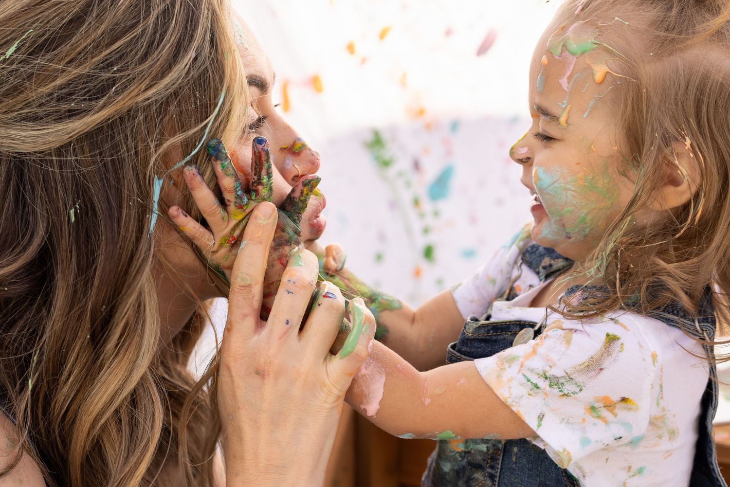 mother daughter family photoshoot, splatter painting session with food colored yogurt, denim overalls, and white t-shirt. mommy + me session