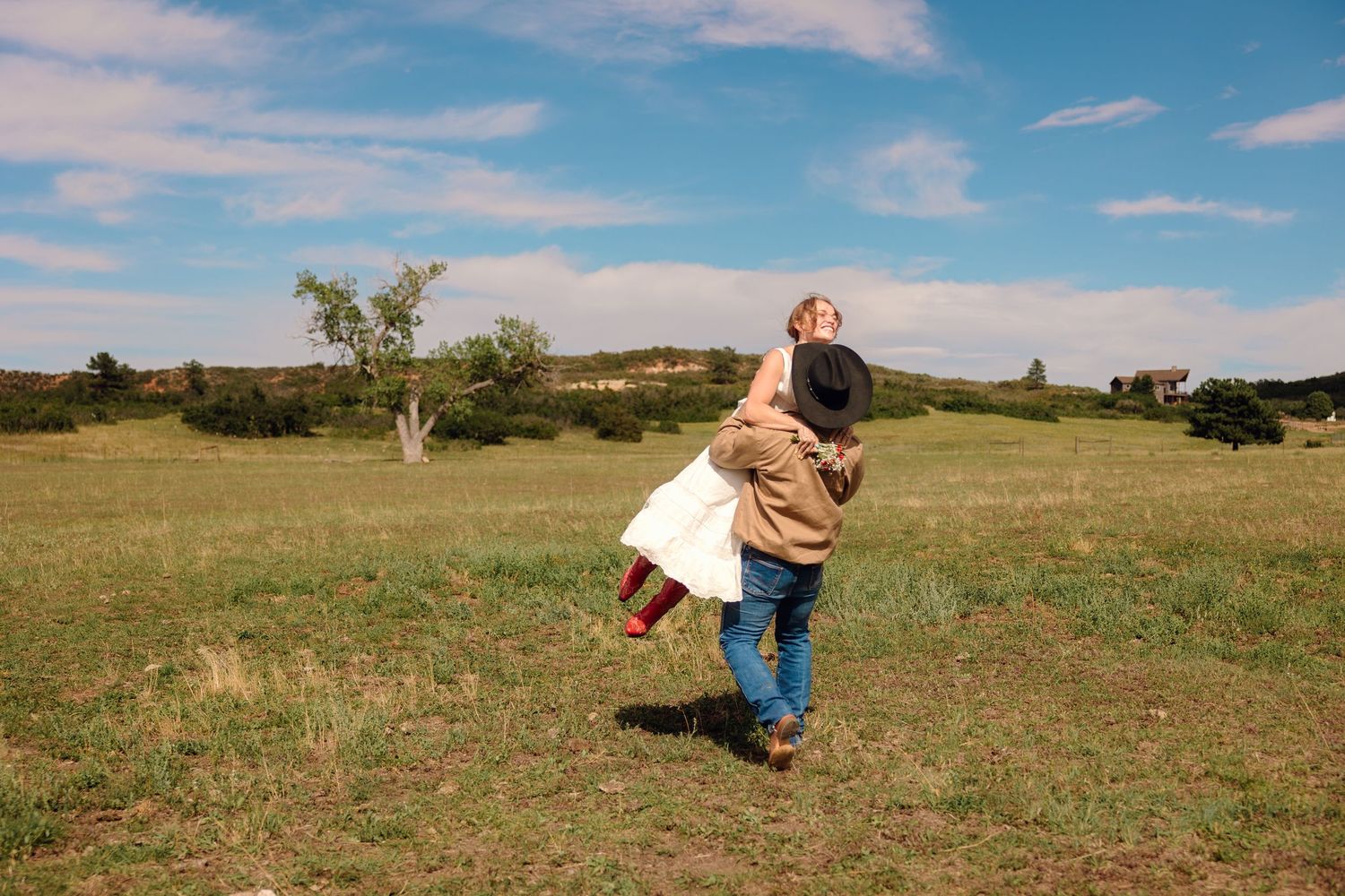 Two children running joyfully through a green meadow under a blue sky on a sunny day.