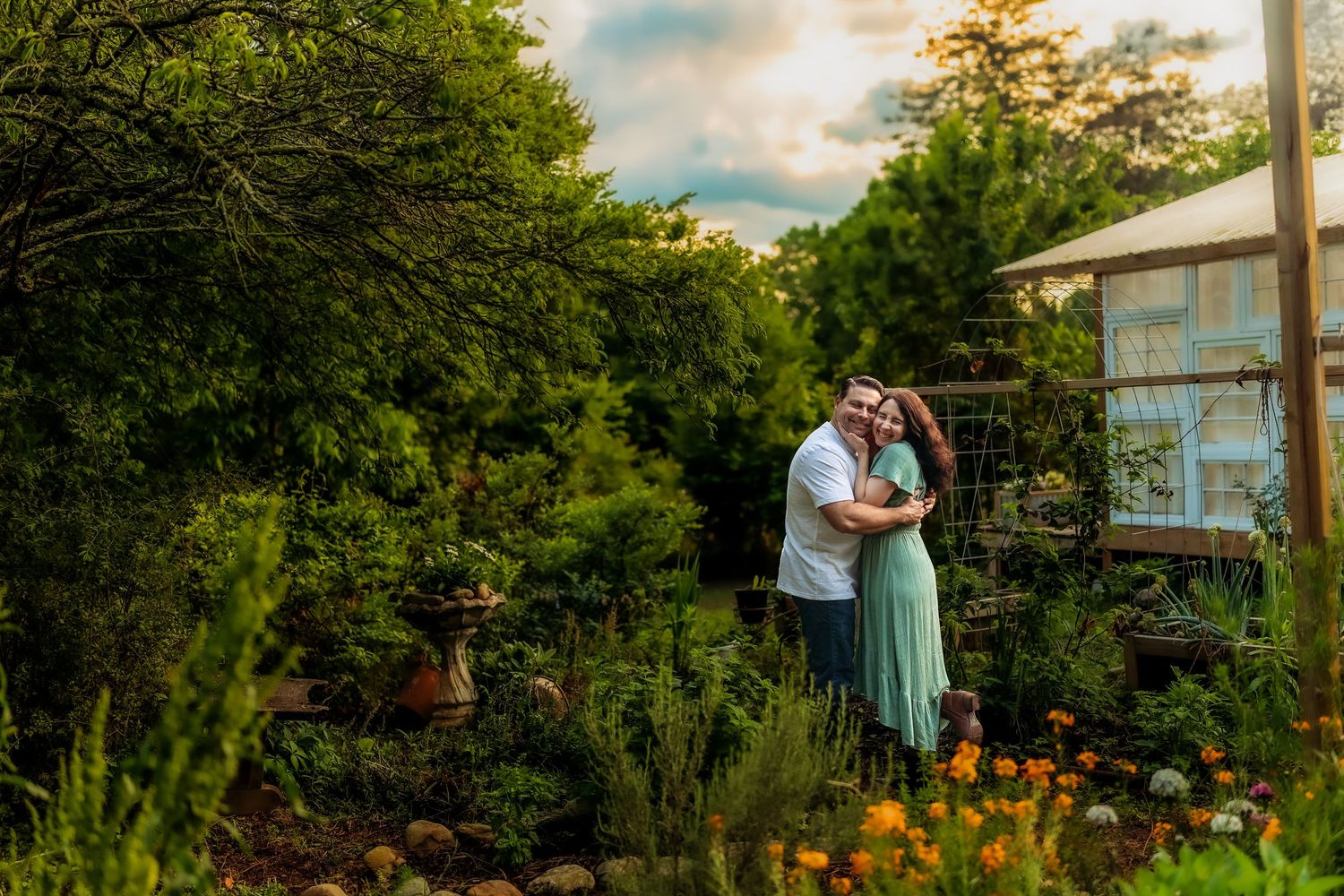 Couple embracing in a lush garden at golden hour, surrounded by colorful flowers and greenery.