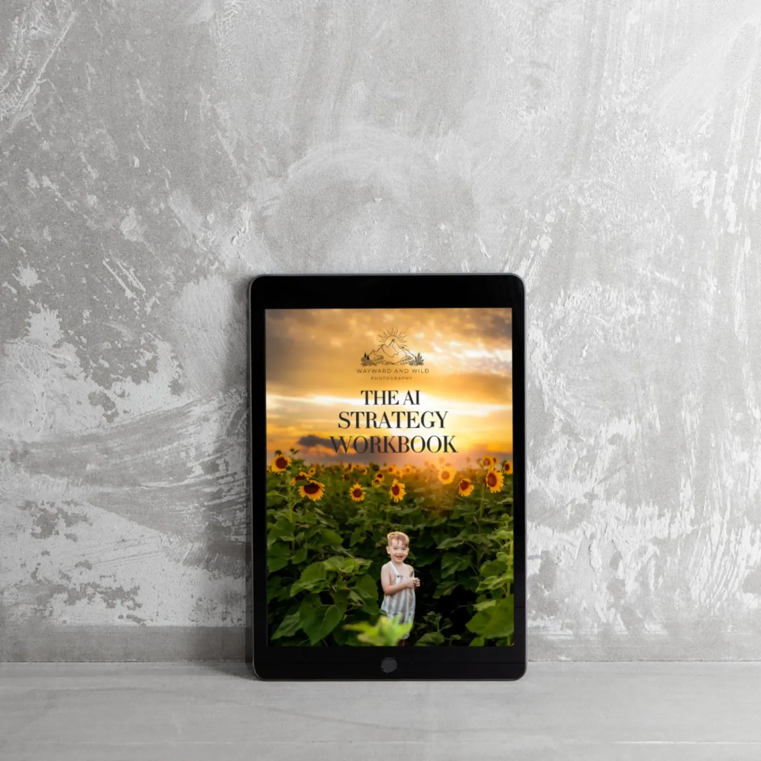 Digital tablet displaying The AI Strategy Workbook cover with a child in a sunflower field at sunset.