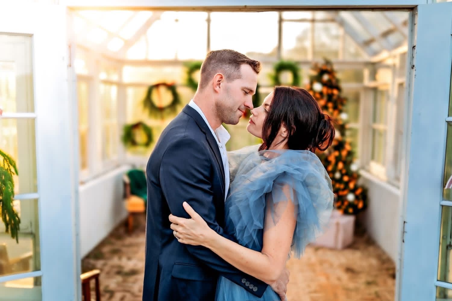 Colorado couples photographer capturing romantic engagement photos in a greenhouse with natural light and candid connection.
