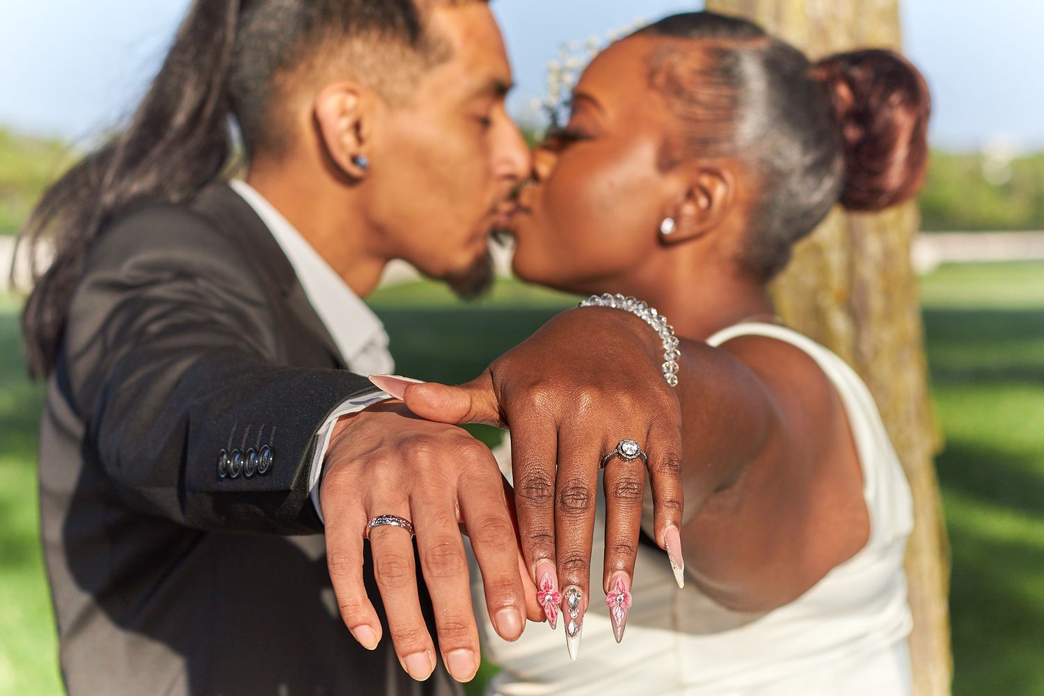 Married couple kissing and showing rings