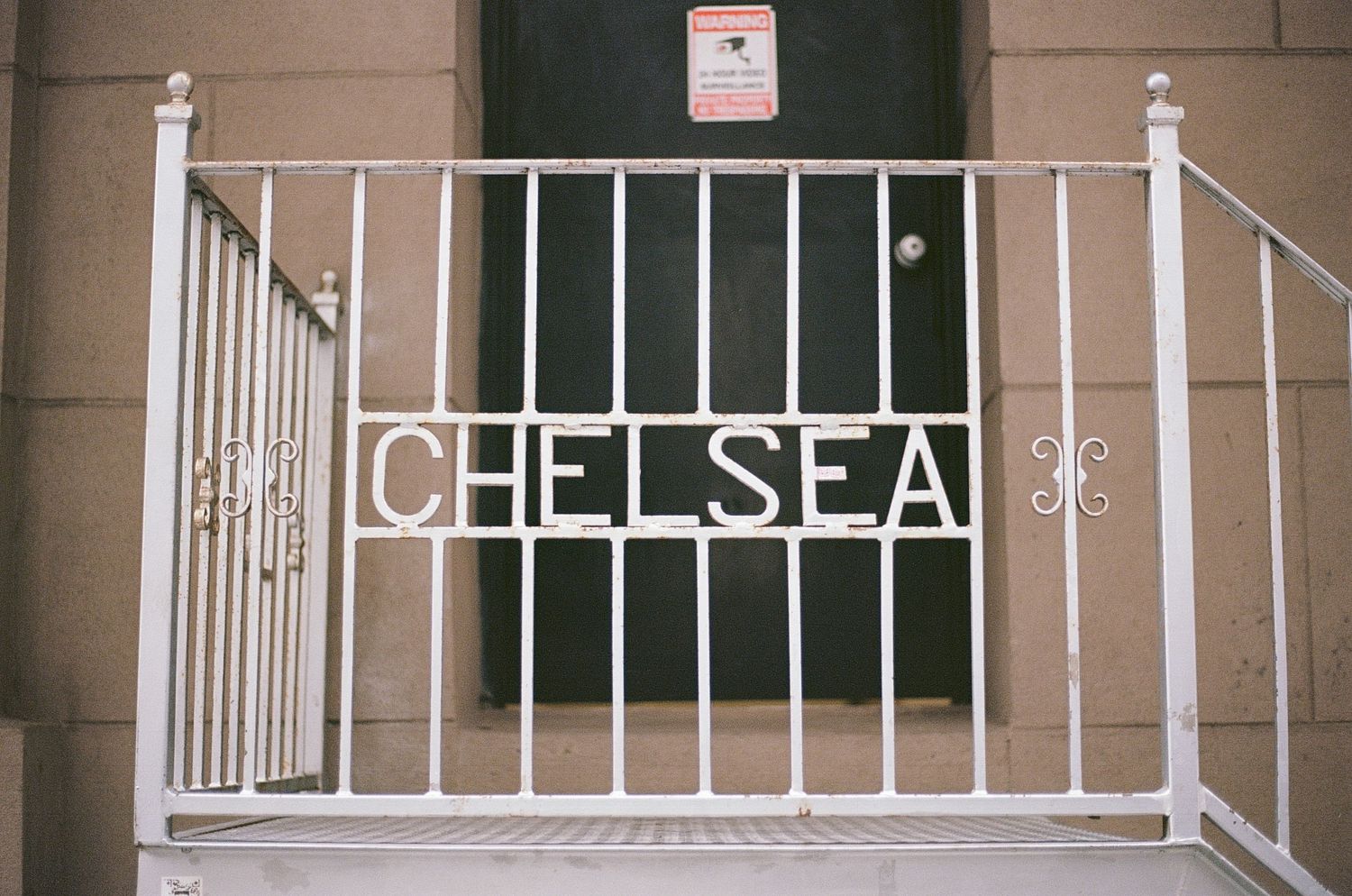 White metal gate with Chelsea spelled out in letters at building entrance.