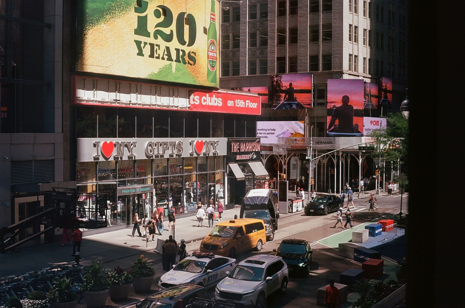Busy Times Square street scene with yellow taxis, pedestrians, and large billboard signs in New York City.