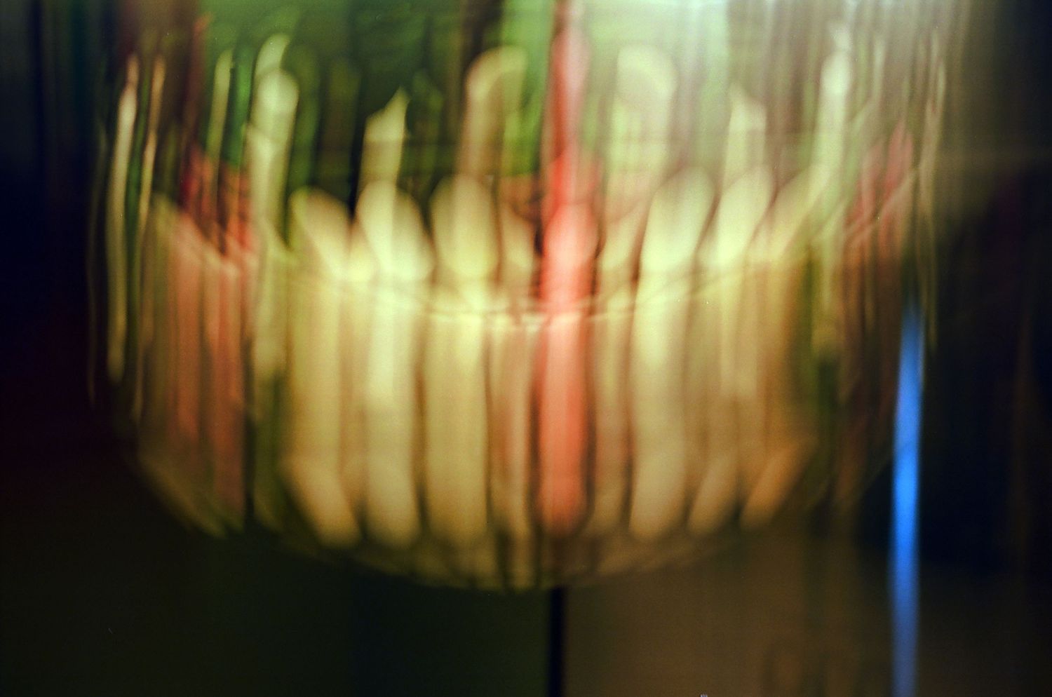 An abstract blurred motion photograph of figures with streaks of green, red, and yellow light.
