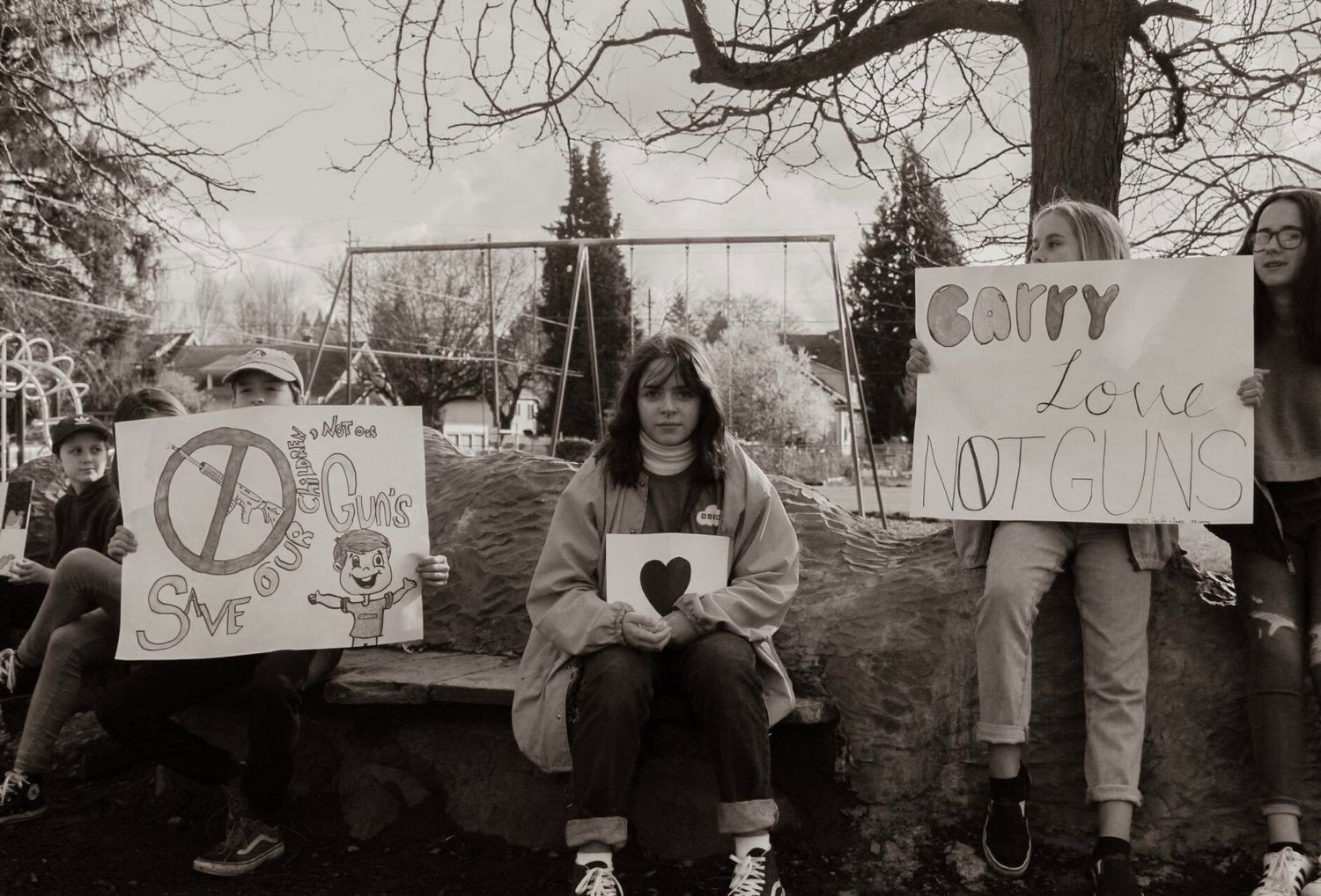 Black and white photo of students holding anti-gun protest signs outdoors.
