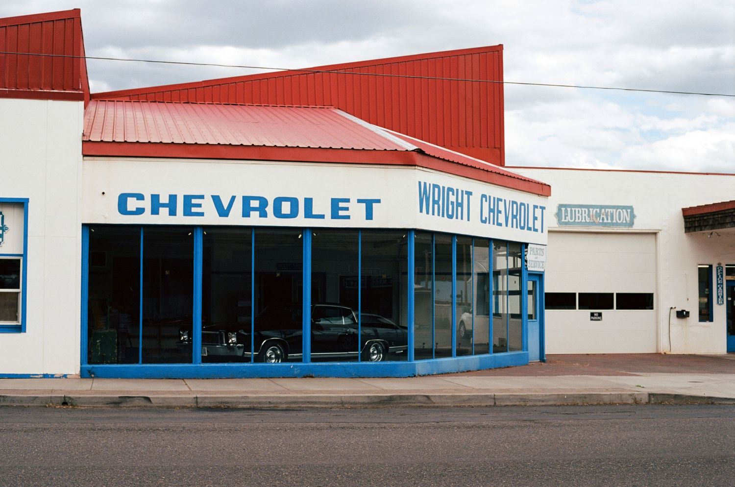 Exterior of Wright Chevrolet dealership with red roof and blue trim in a small American town.