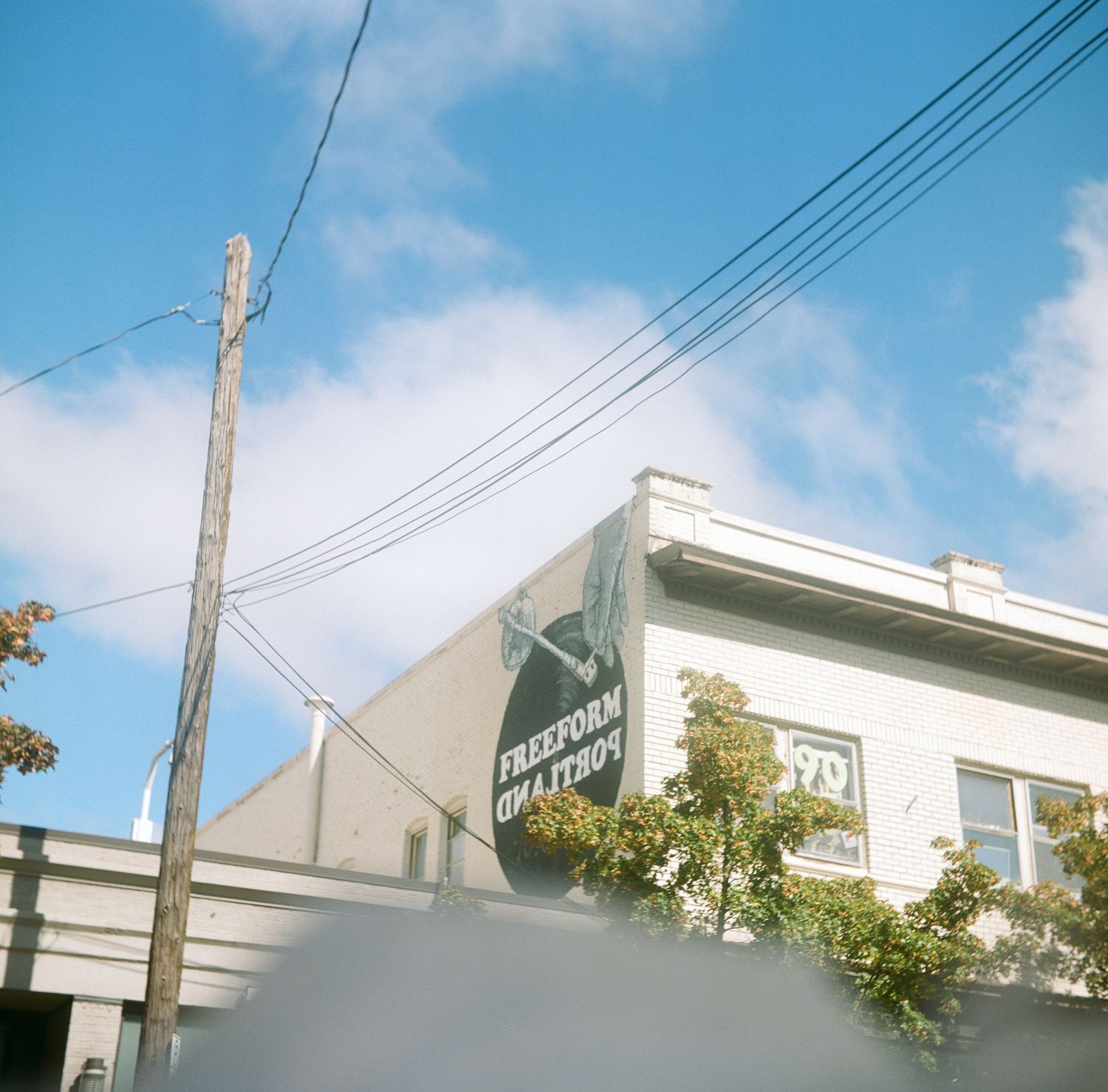 A building with a Freeform Creation mural sign under blue skies with utility wires overhead.