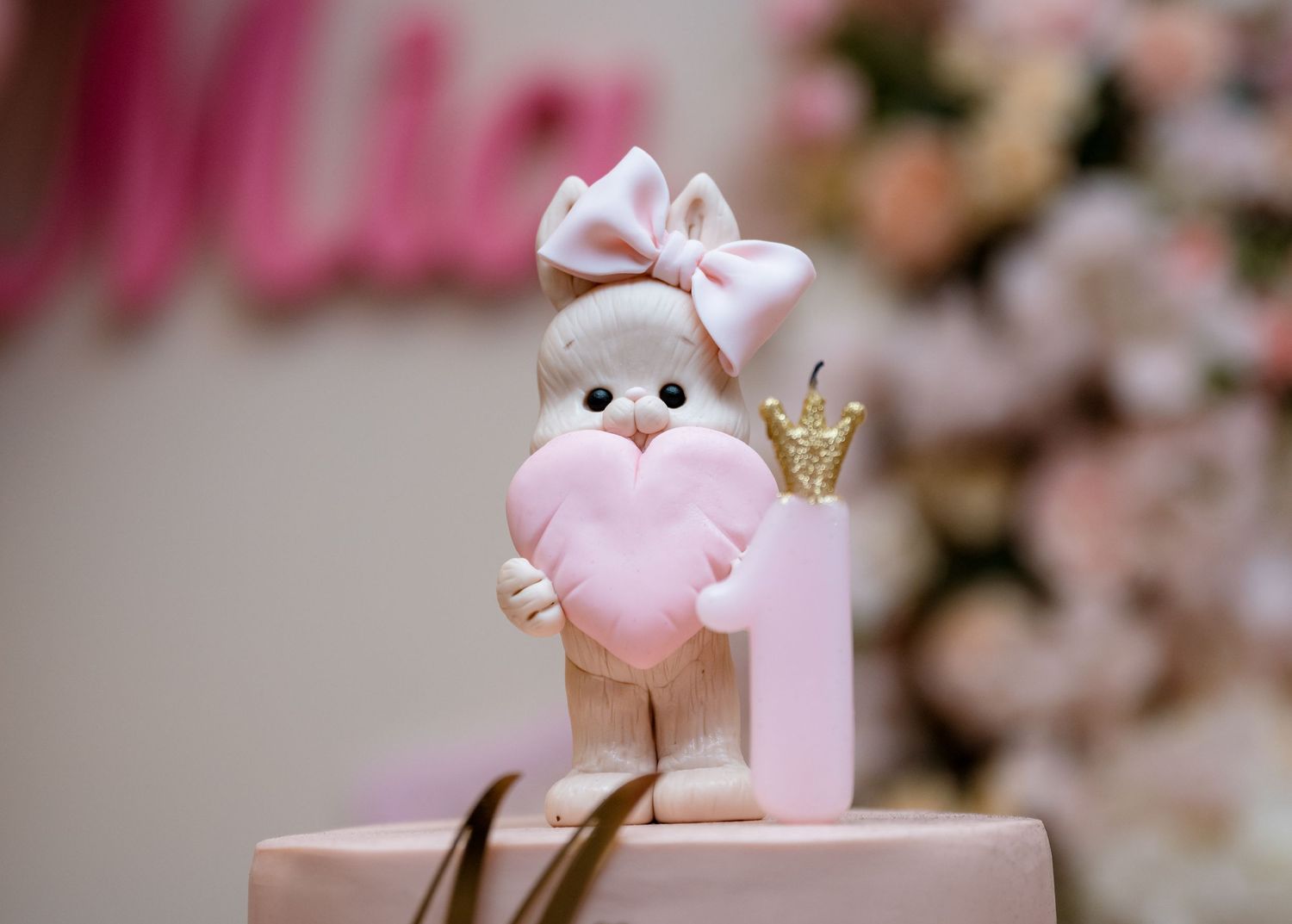 Adorable fondant bunny cake topper holding a pink heart for a first birthday cake.