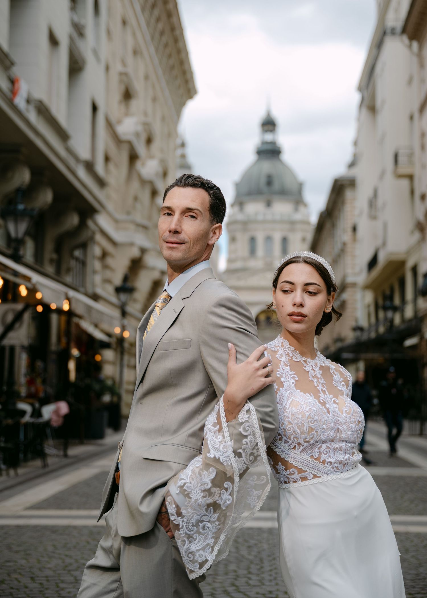 Elegant bride and groom posing on European street with St. Stephen's Basilica Budapest in background.
