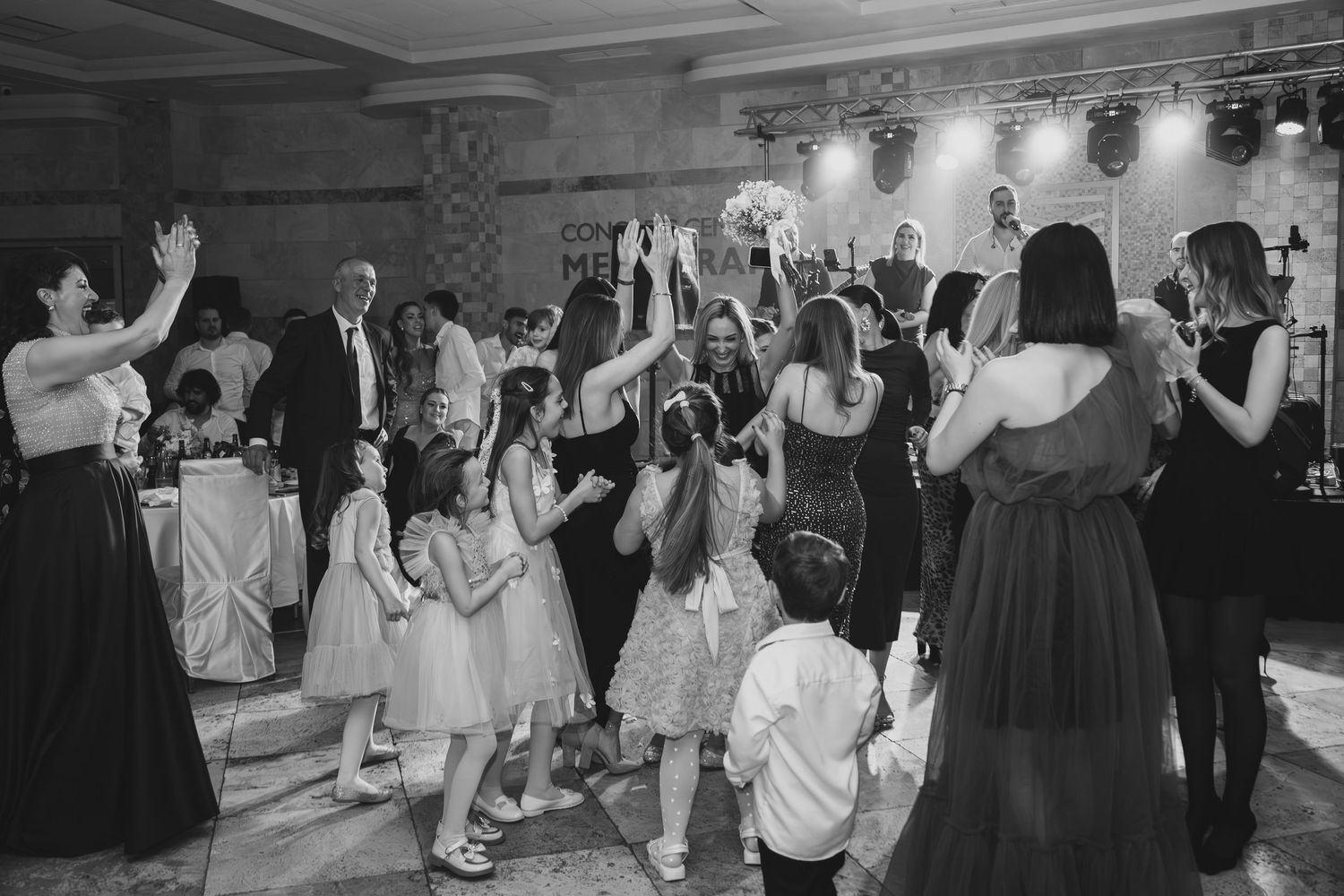 Wedding guests dancing and celebrating on crowded reception dance floor in black and white photo.