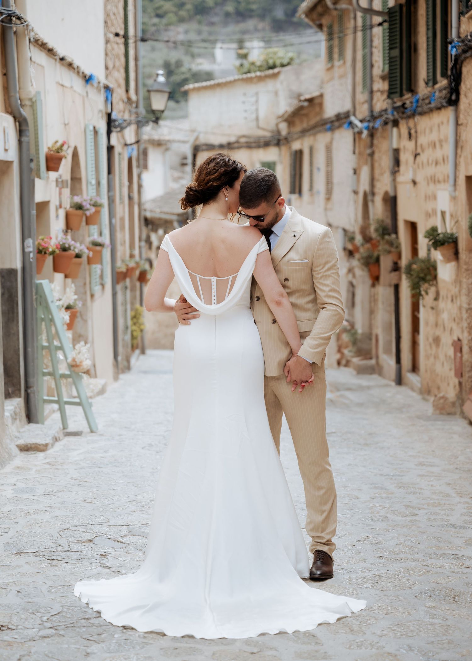 Wedding couple shares tender moment in charming narrow cobblestone street lined with stone buildings.