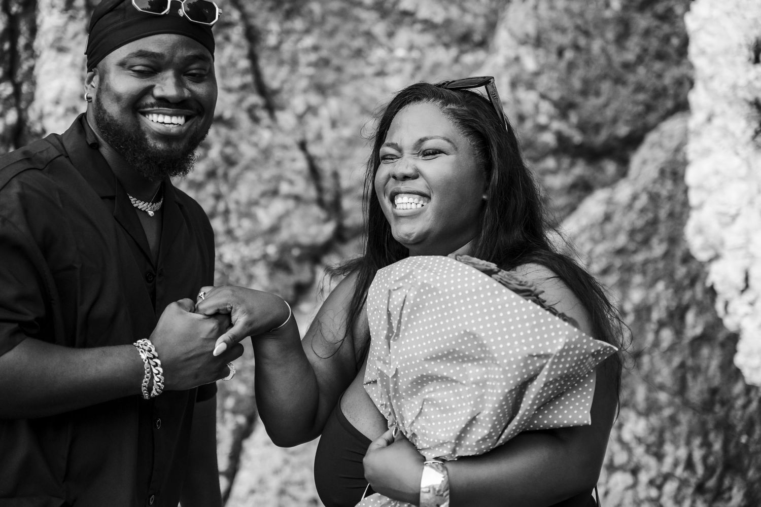 A happy couple laughs together in a black and white photo after a marriage proposal outdoors.