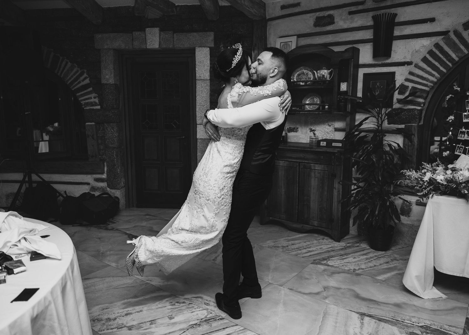 Groom lifting bride during romantic first dance at wedding reception.
