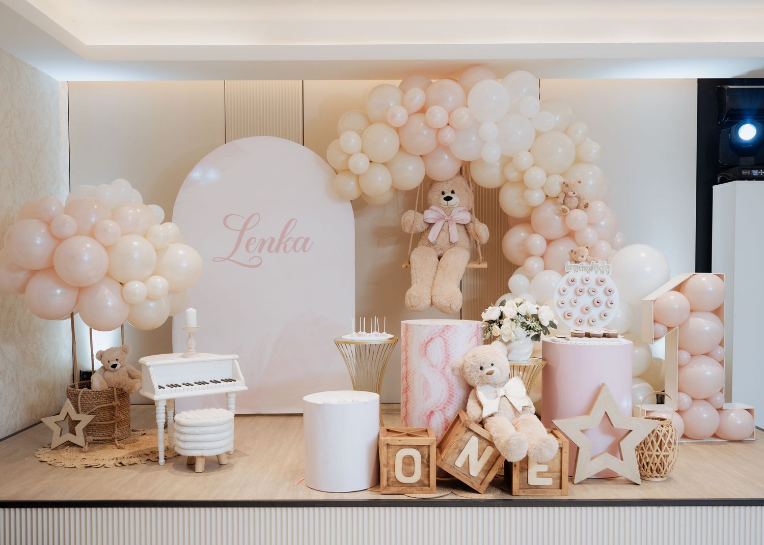 Pink and white first birthday party setup named Lenka with balloons, teddy bears, and ONE blocks.