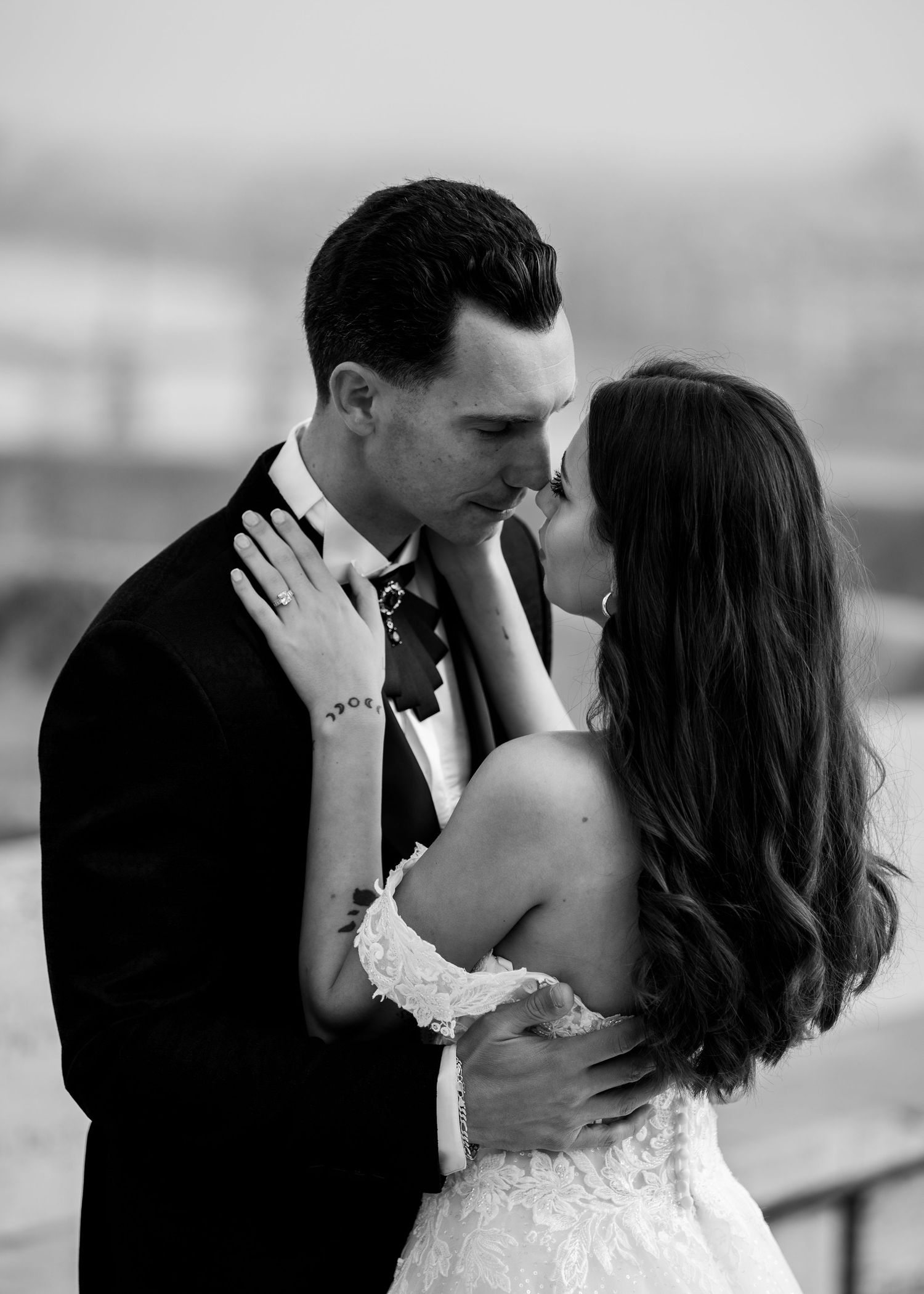 Black and white photo of bride and groom sharing a romantic kiss at their wedding ceremony.