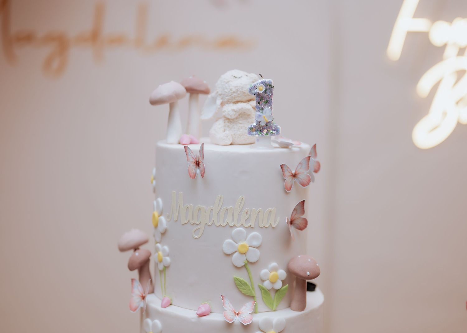 Close-up of a white birthday cake with butterfly and floral decorations inscribed with the name Magdalena.