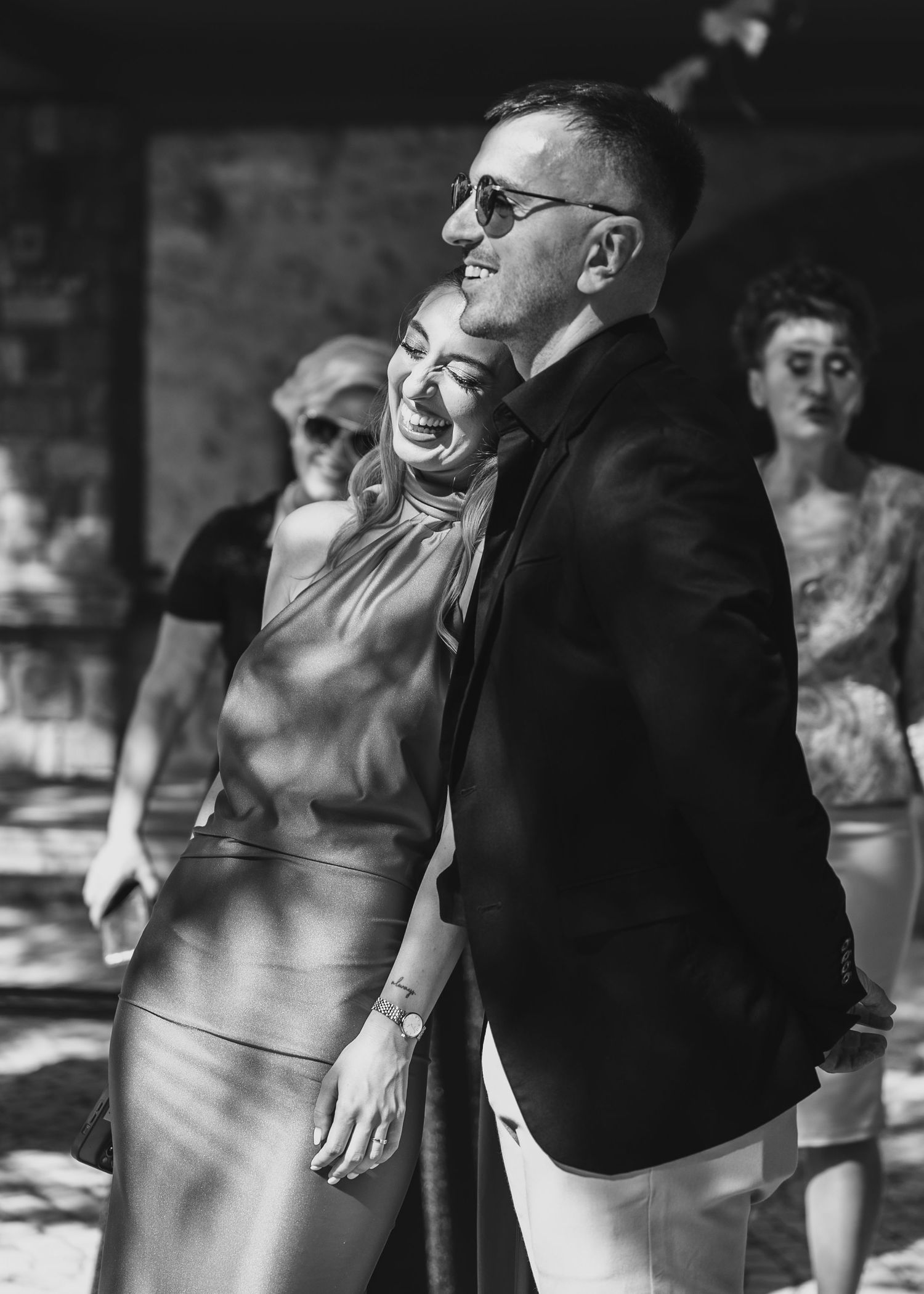 Black and white photo of smiling couple embracing at wedding reception in elegant attire.