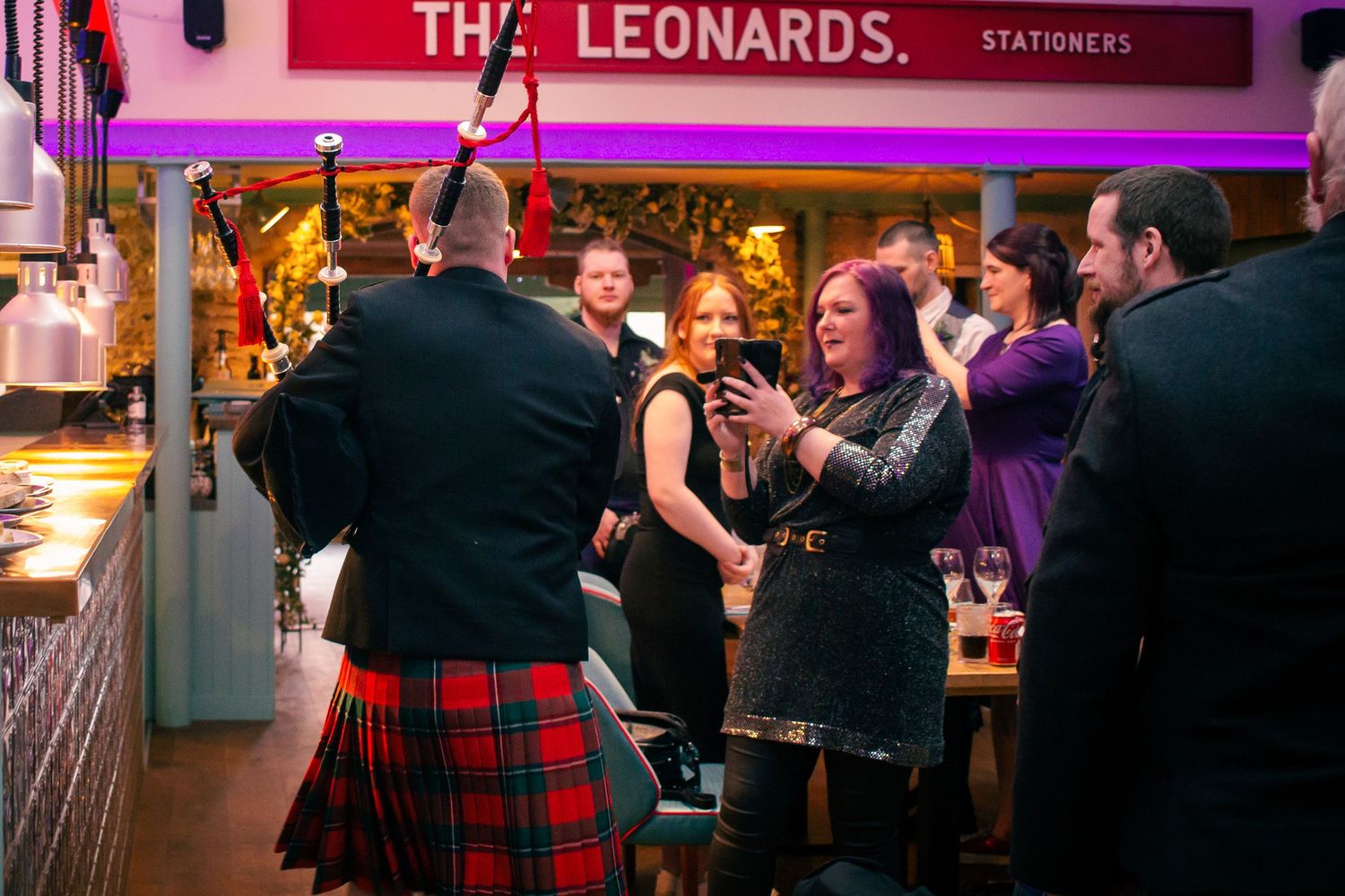 Guests celebrate at Tat the storehouse, kirkwall, with a man in red tartan kilt entertaining the lively crowd.