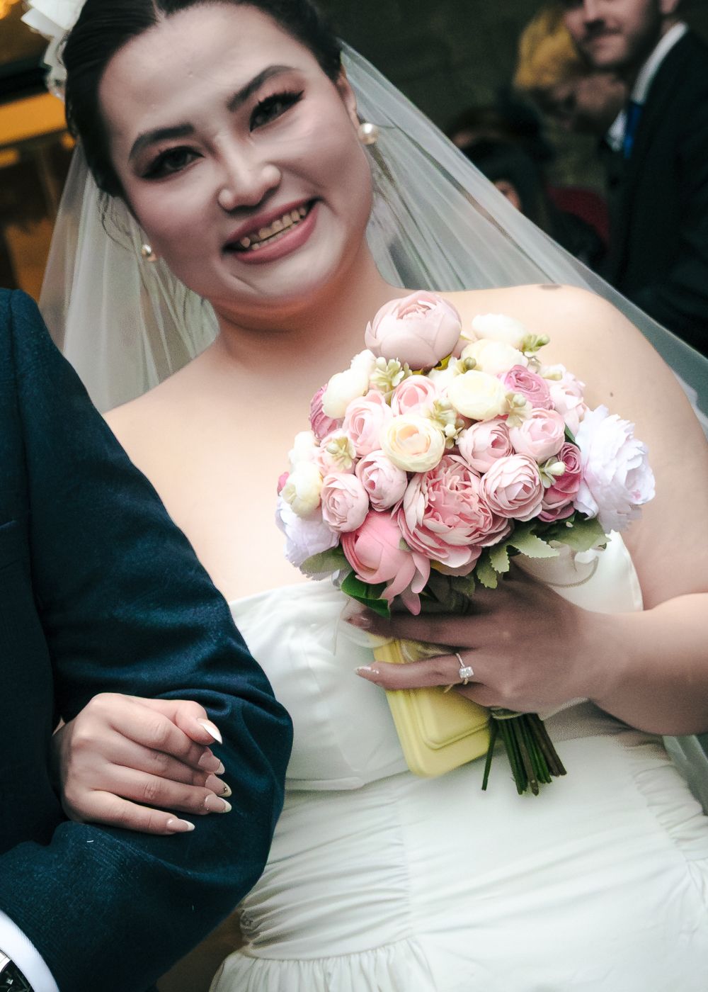 Radiant bride in strapless white gown and veil holding a lush pink peony and rose bridal bouquet taken by Orkney Photographer