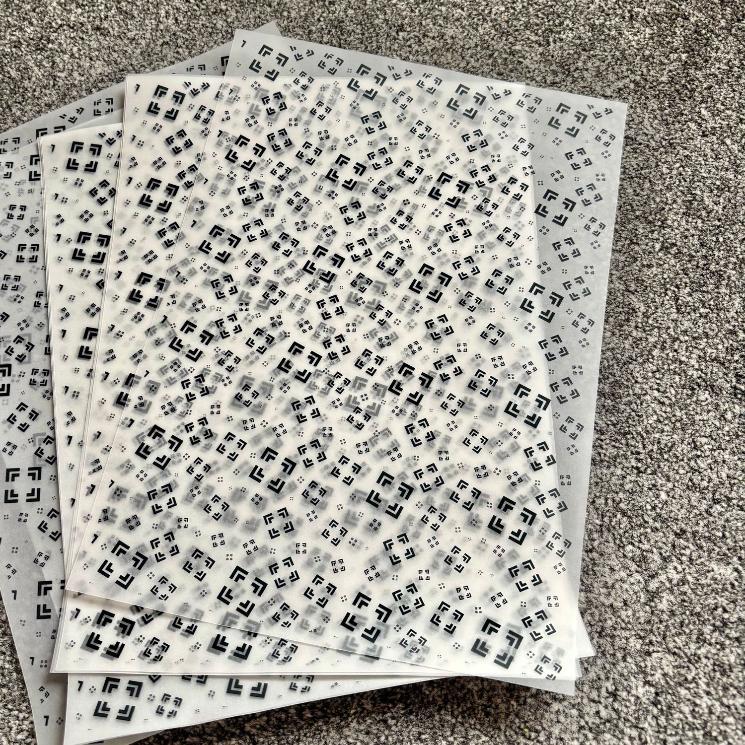 Stack of white sheets covered in dense black and white QR code patterns arranged in a grid layout.