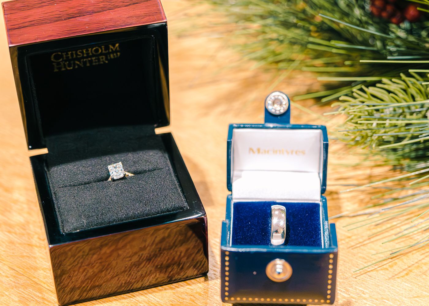 Two elegant wedding rings displayed in luxury jewelry boxes on wooden surface taken by Orkney Photographer