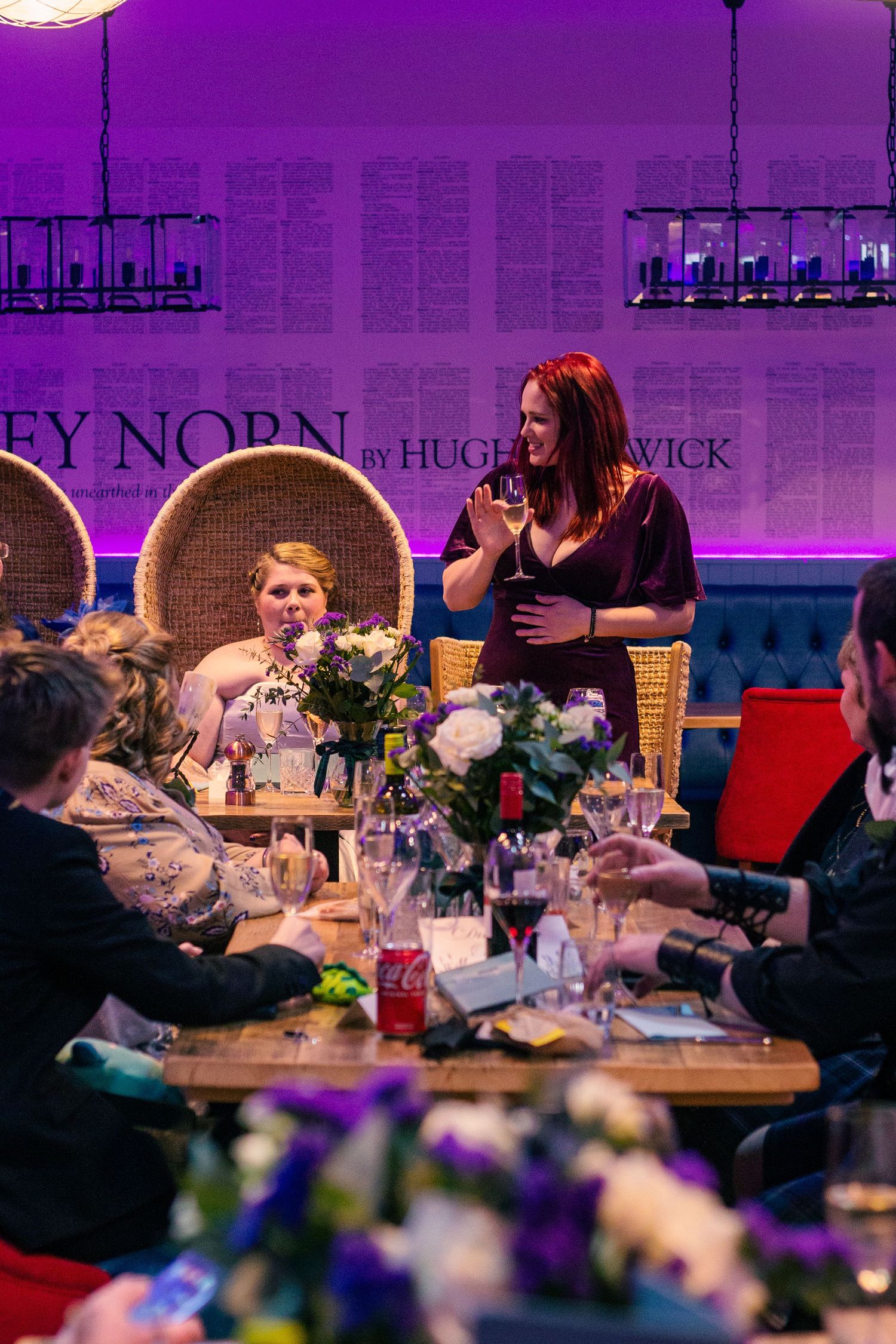 Women socializing at an elegant restaurant dinner event with purple ambient lighting and floral centerpieces at the storehouse, kirkwall.