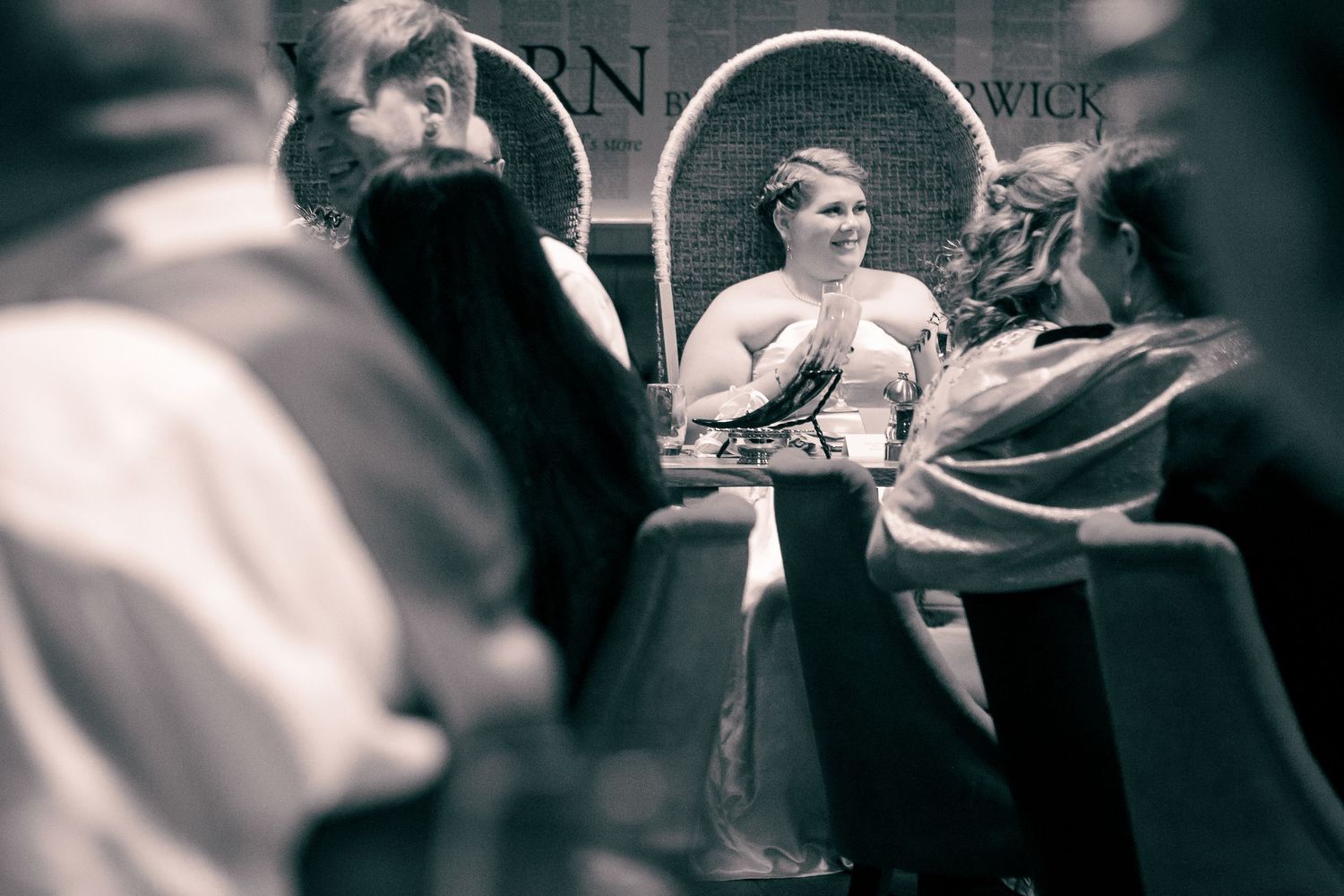 Black and white photo of a speaker presenting at a panel discussion in a brick-walled venue with an engaged audience at the storehouse, kirk