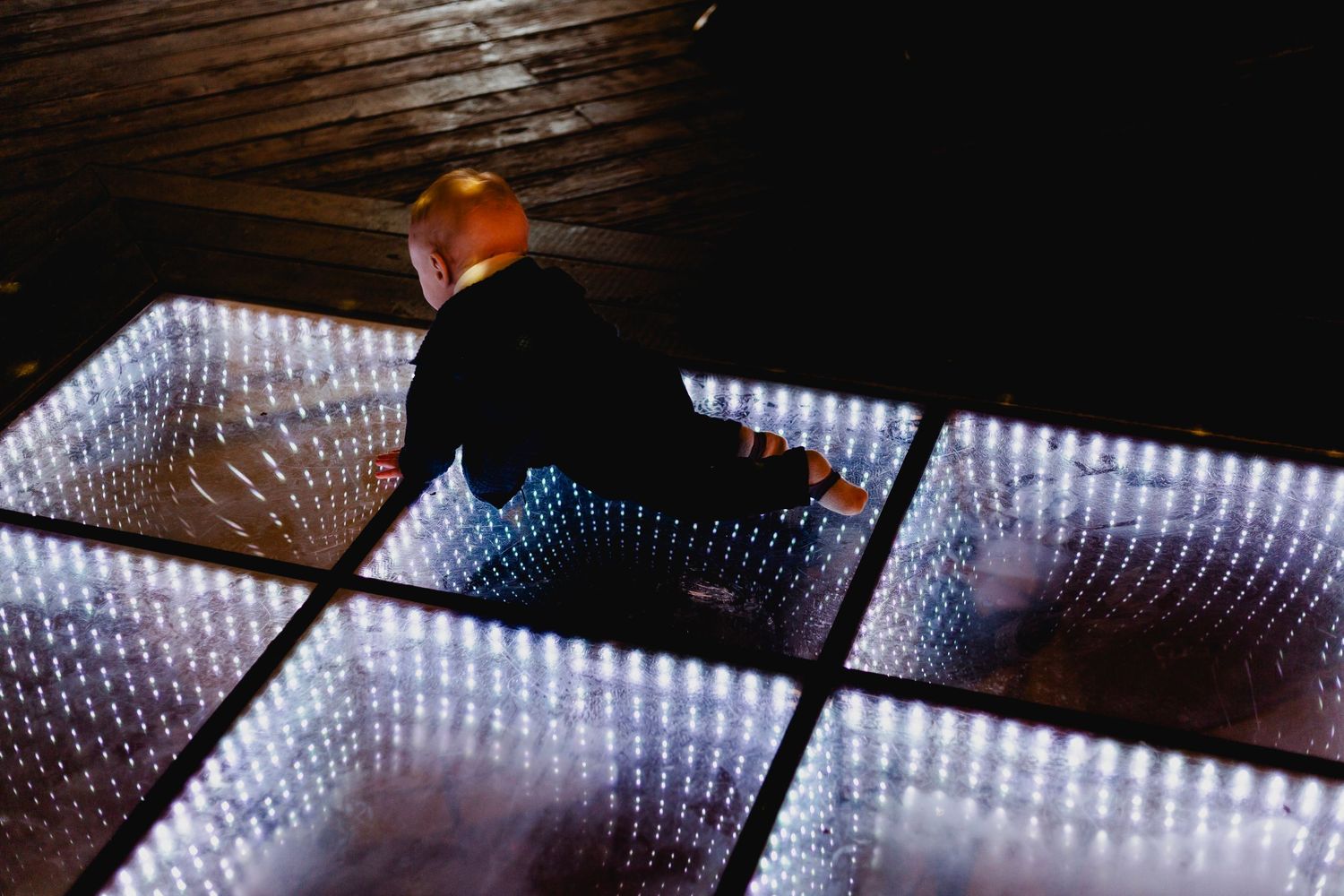 Baby sitting on illuminated LED infinity mirror dance floor tiles at a wedding venue