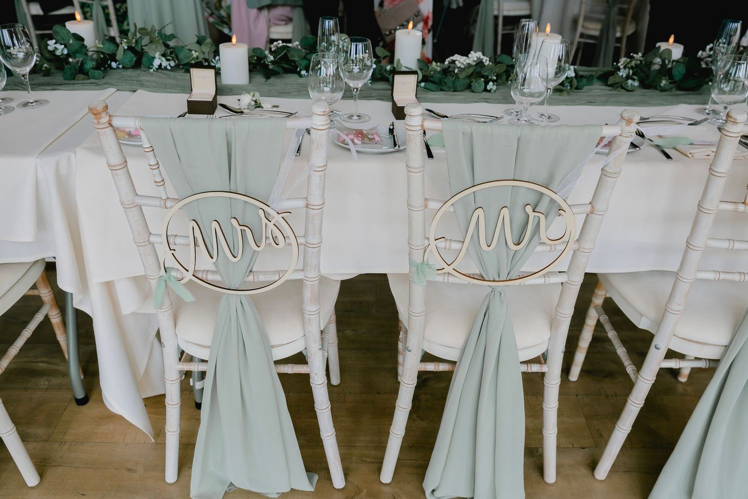 Mr and Mrs chair signs with sage green ribbon bows at elegant wedding reception table.