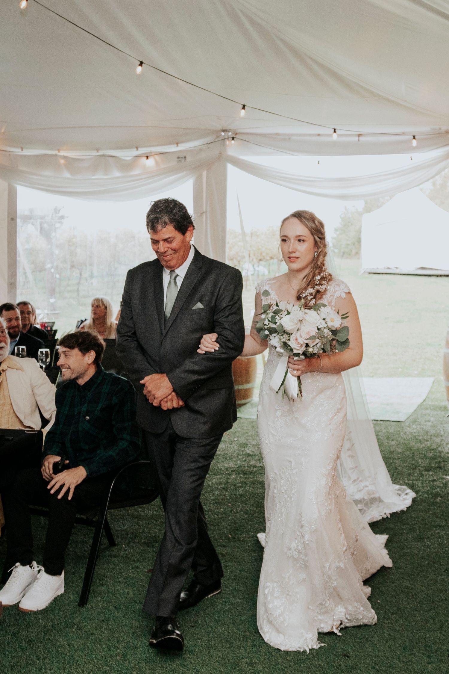 Wedding ceremony processional under white tent with string lights.